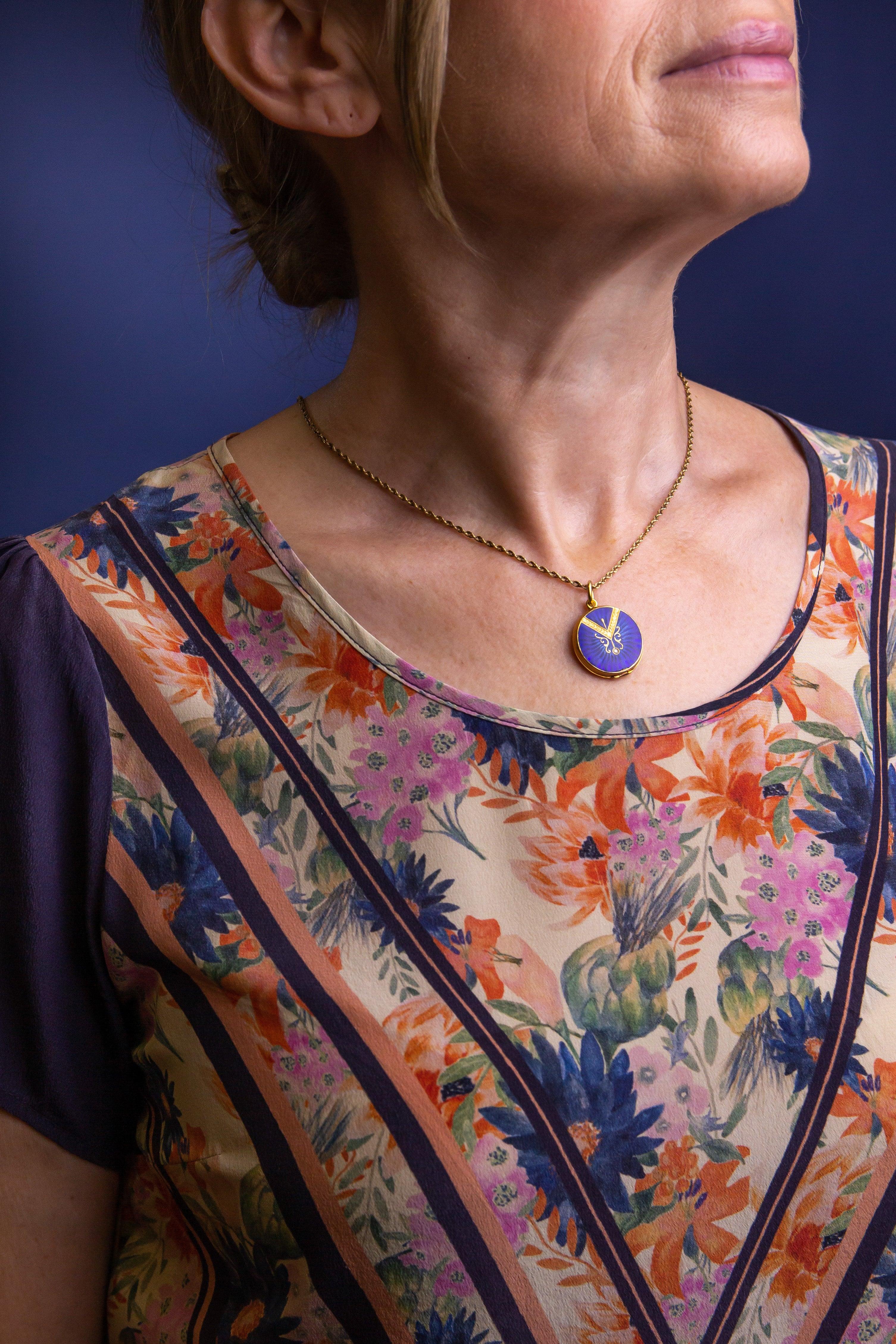 This round yellow gold locket is likely French in origin and features beautiful blue guilloche enamelling and a central single cut diamond. The rear back panel of the locket is plain yellow gold while the front panel of the locket features a Belle