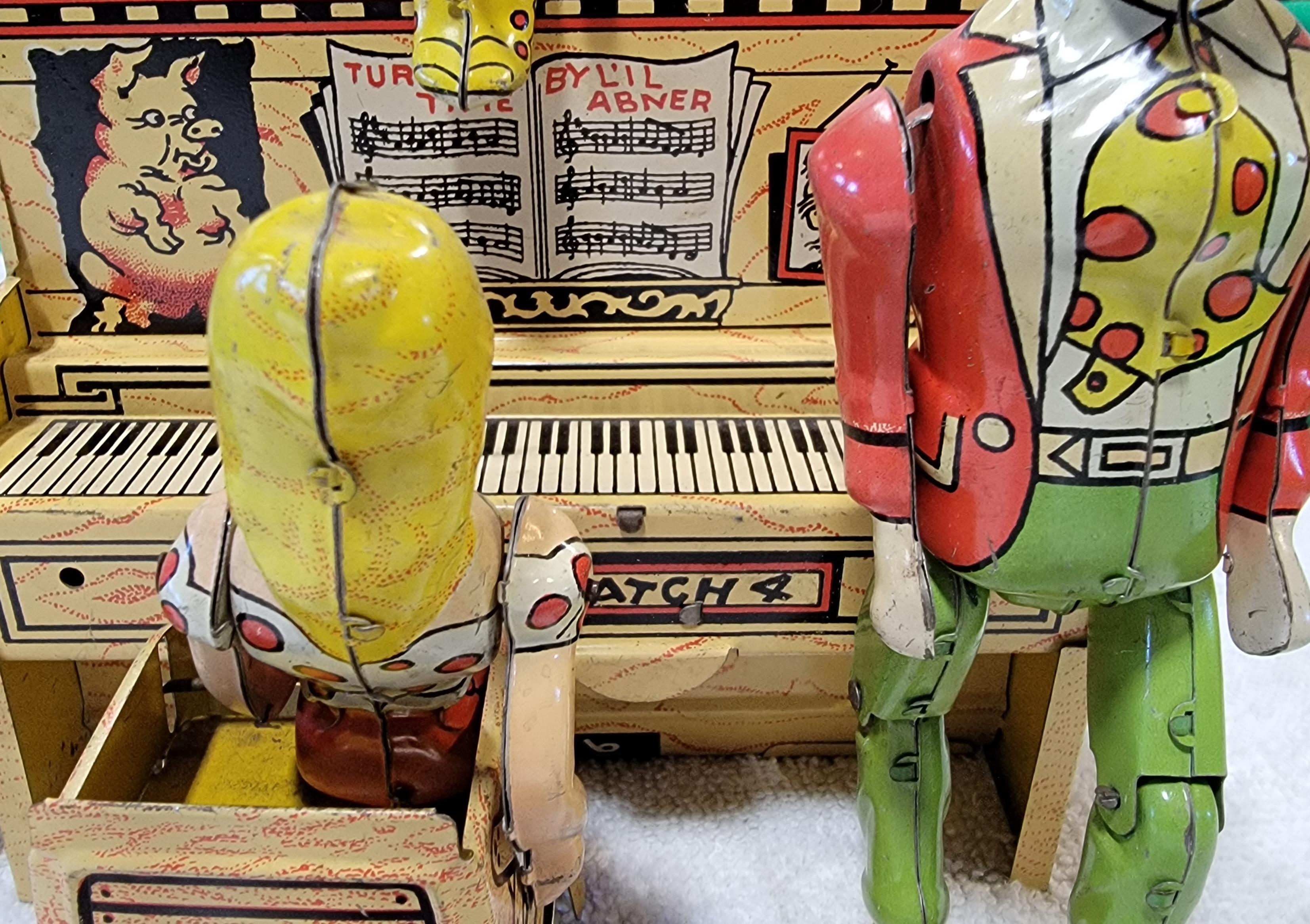 Unique Art Manufacturing Toy Company. Circa. 1940’s. Tin Lithographed Windup “Li’l Abner and his Dogpatch Band” . In excellent, original working condition. Tin wind up toy featuring Li'l Abner as singer, a band leader, drummer and a piano with