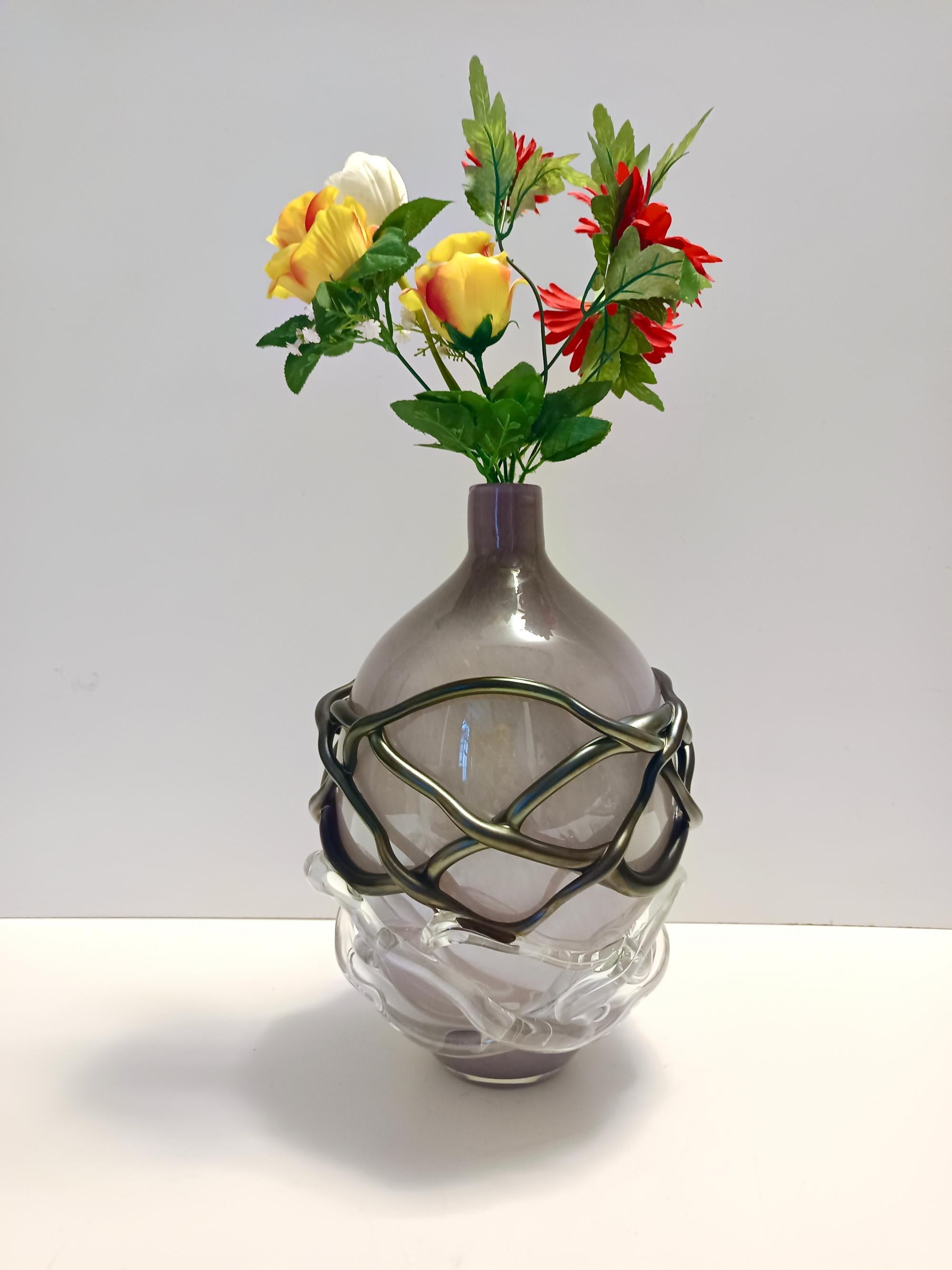 Realizzato in Italia da Sergio Costantini, anni '90
Questo vaso è realizzato in vetro di Murano soffiato a mano e acidato con un leggero effetto pulegoso. Presenta inoltre un reticolo trasparente e nero iridescente. 
Si tratta di un pezzo vintage,