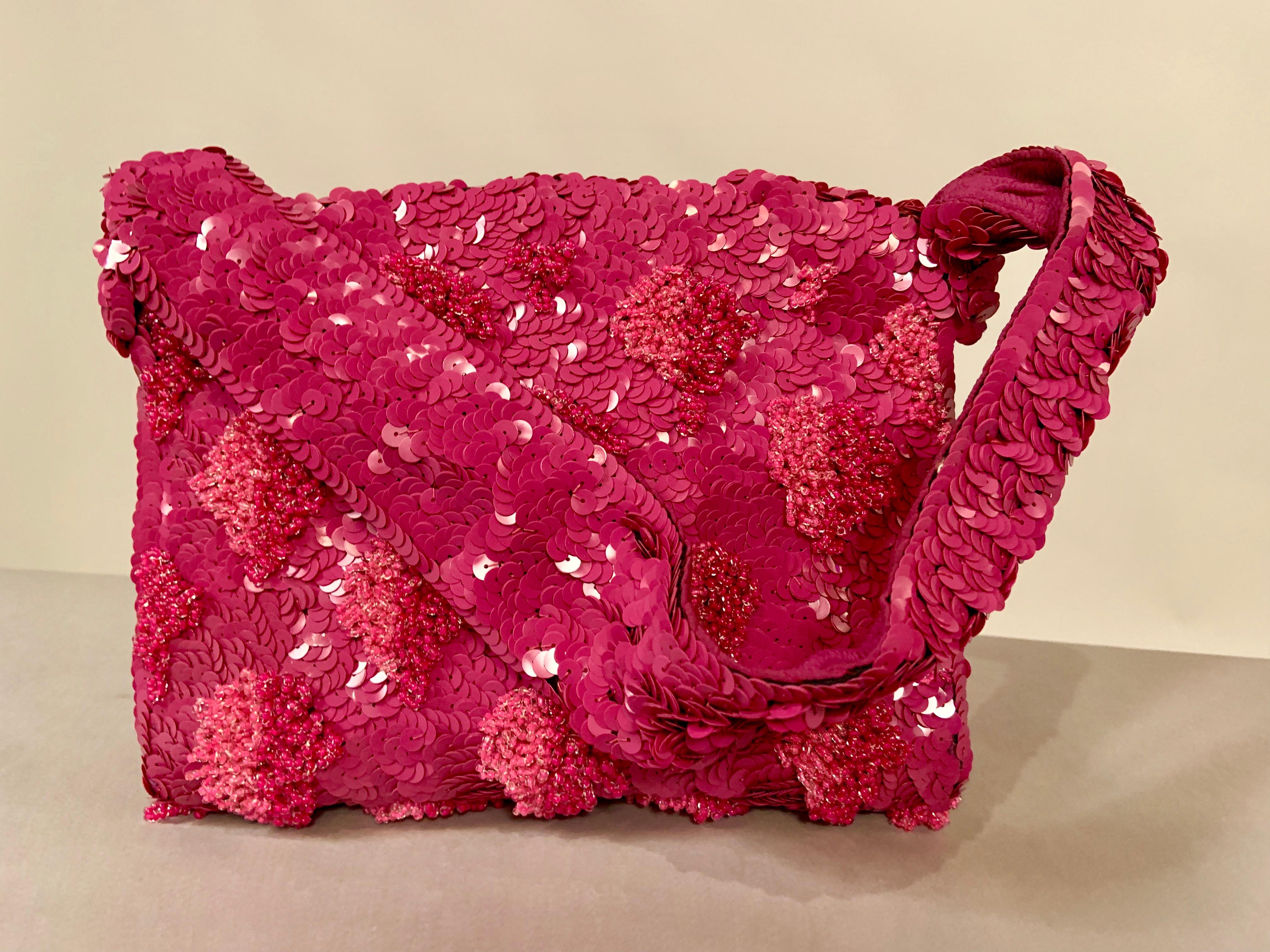 Lilac sequins are sewn in a circular pattern on  to to liac silk crepe. This is then rebeaded with loops of caviar beads in shades of lilac to pale pink in a floral or grape cluster motif. The bag has a wide beaded top handle, and a hinged opening.