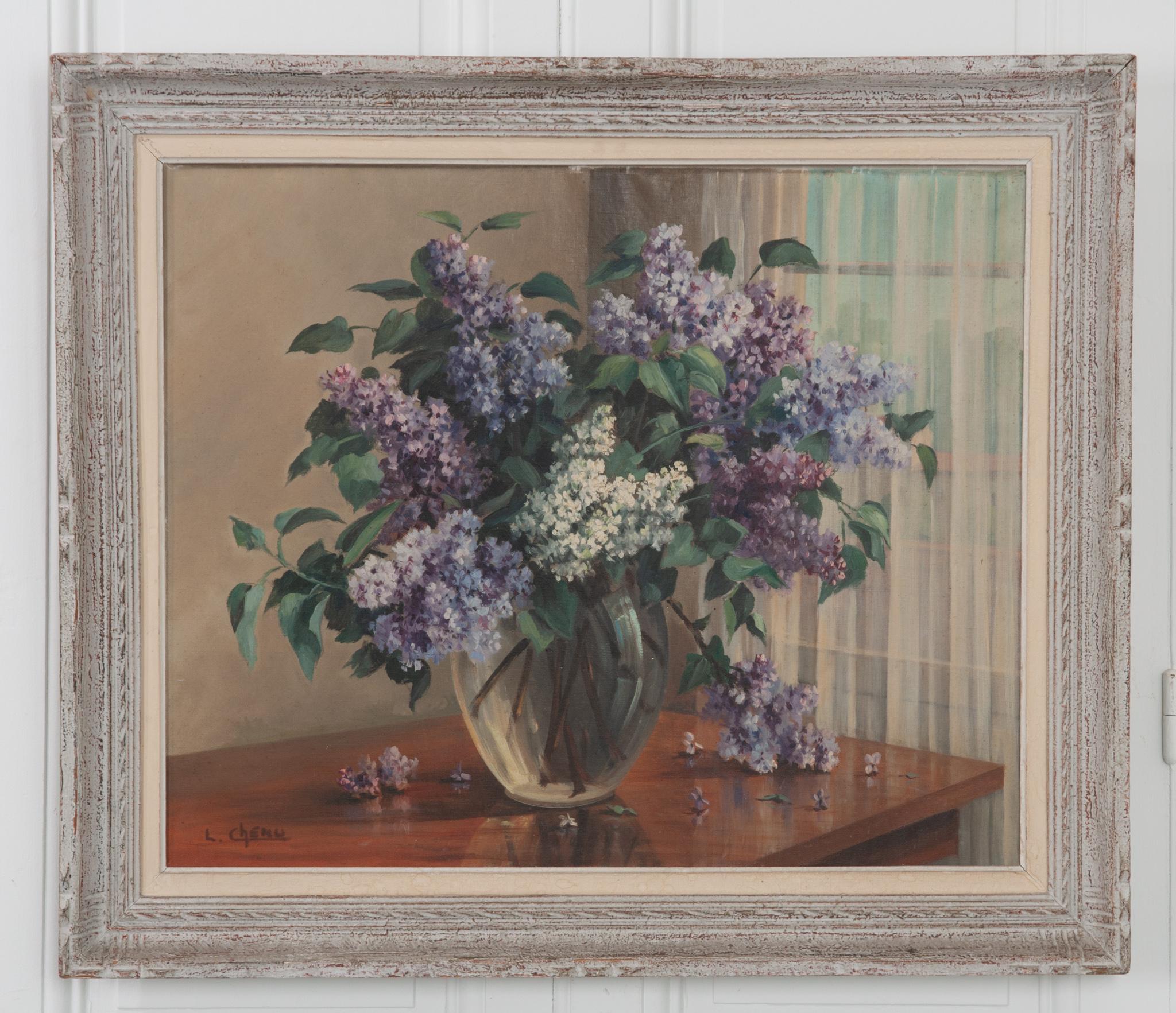 This framed oil on canvas was painted by French artist Lucien Chenu. An overflowing vase of beautiful lilacs sits near a bright window, painted in a way that conveys the loveliness in everyday objects. The frame has layers of character that matched
