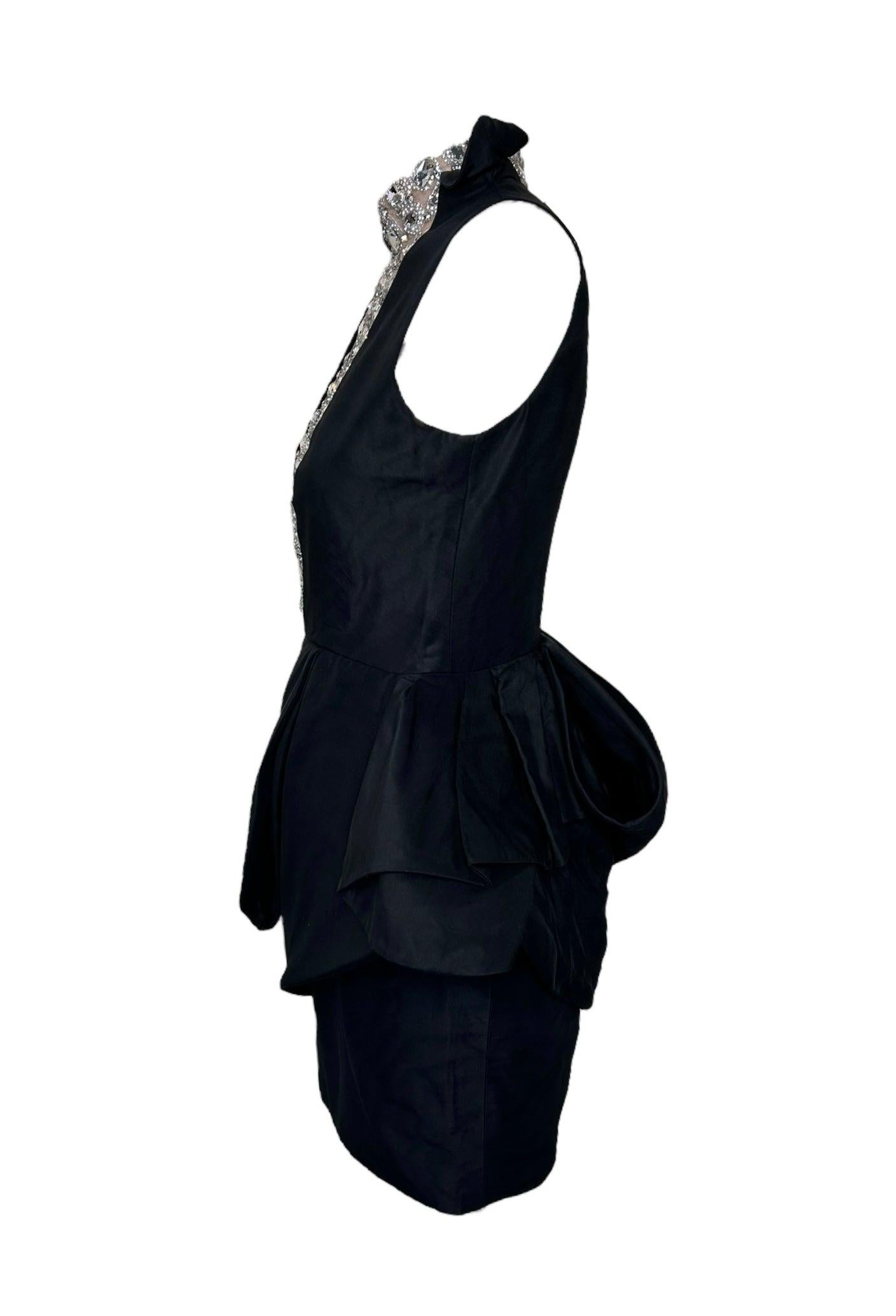 Este increíble vestido de cóctel negro, diseñado por una de las mejores diseñadoras francesas, Liliane Romi, destila lujo y modernidad. El impresionante escote de pedrería añade un toque de elegancia. Con peplums con aros de alambre