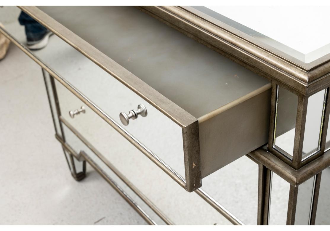 Fine mirrored chest with antiqued gray wood frame. With an inset beveled mirror top and three long drawers with nickel finish knob pulls. The sides and supports made in segments. Raised on square tapering mirrored legs. 
L. 41 3/4