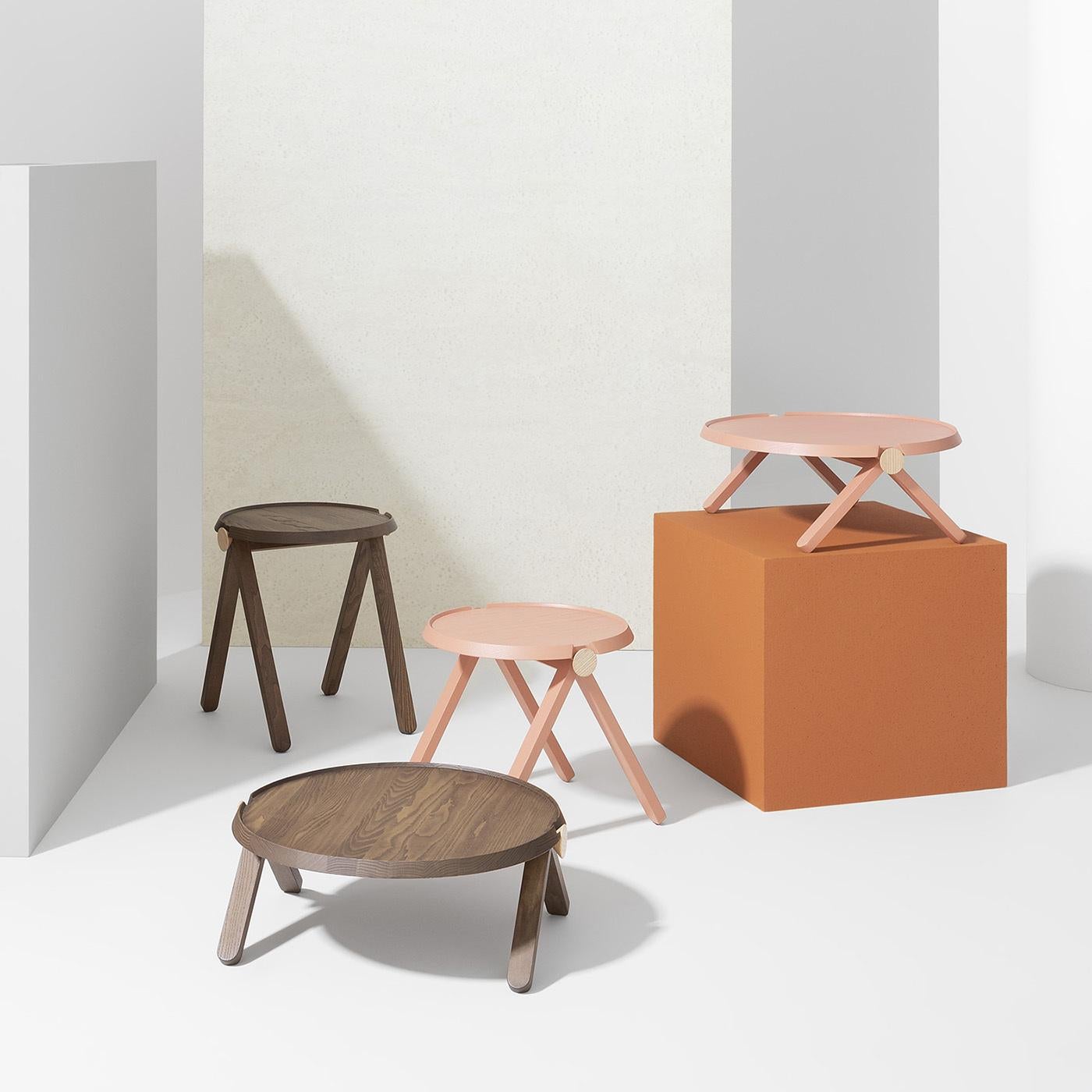 La armonía de las curvas se celebra en esta vanguardista mesa de centro de Studioventotto. Su estructura de madera de haya lacada en un glamuroso tono salmón ofrece una solución perfecta para servir repostería en ocasiones especiales o como elegante