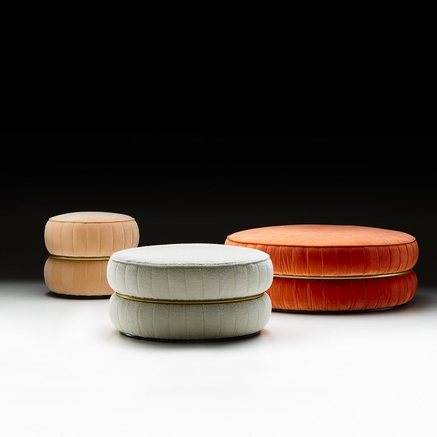 Combinaison élégante de fonction et d'esthétique, ce pouf dégage un charme intemporel et polyvalent. Enrichi d'un anneau métallique finition or mat rehaussant la douceur du revêtement en tissu inamovible fini par de précieuses coutures nervurées, il