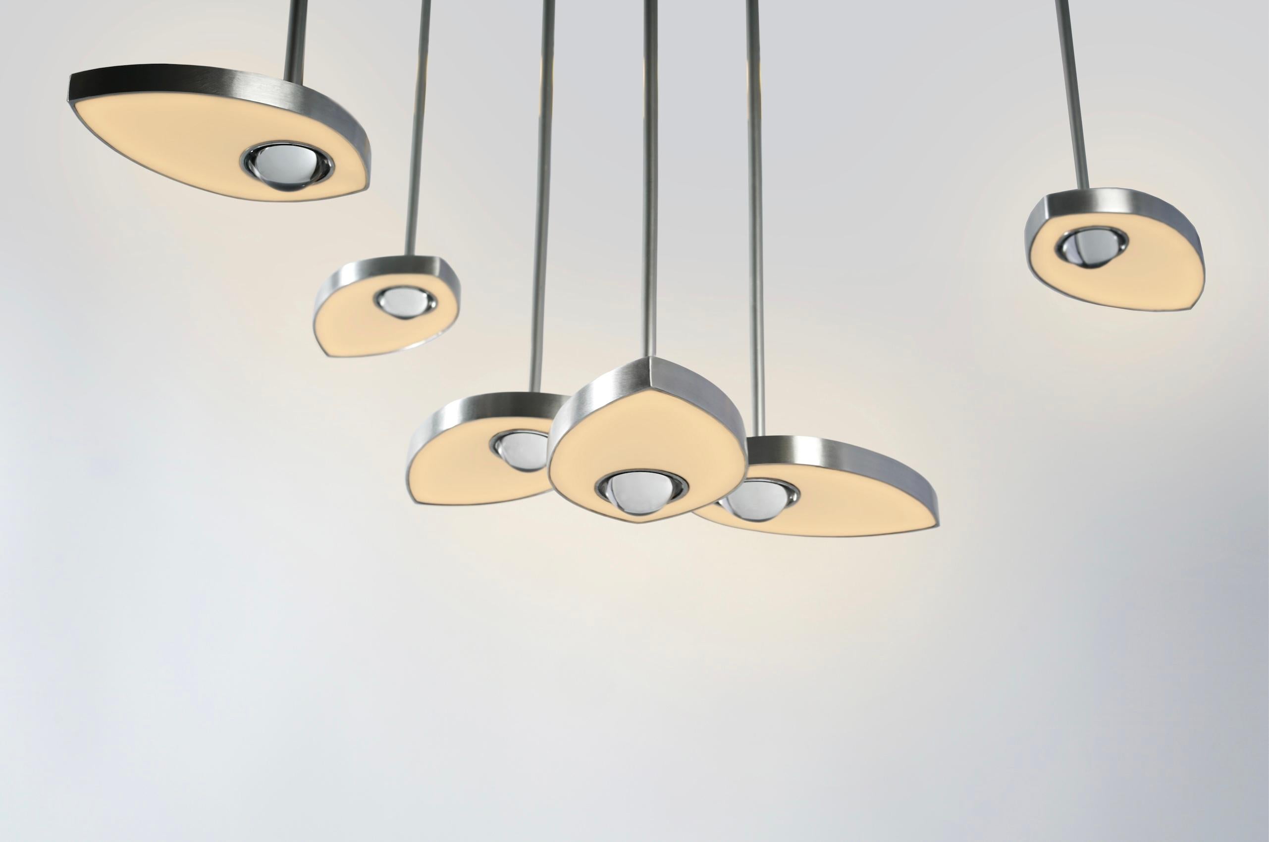 Lilly è un lampadario contemporaneo che sfida la differenziazione tra stanza e oggetto. Formata da petali in ottone massiccio fresato, ogni sorgente luminosa a LED contiene una singola semisfera di cristallo che assorbe e riflette l'ambiente