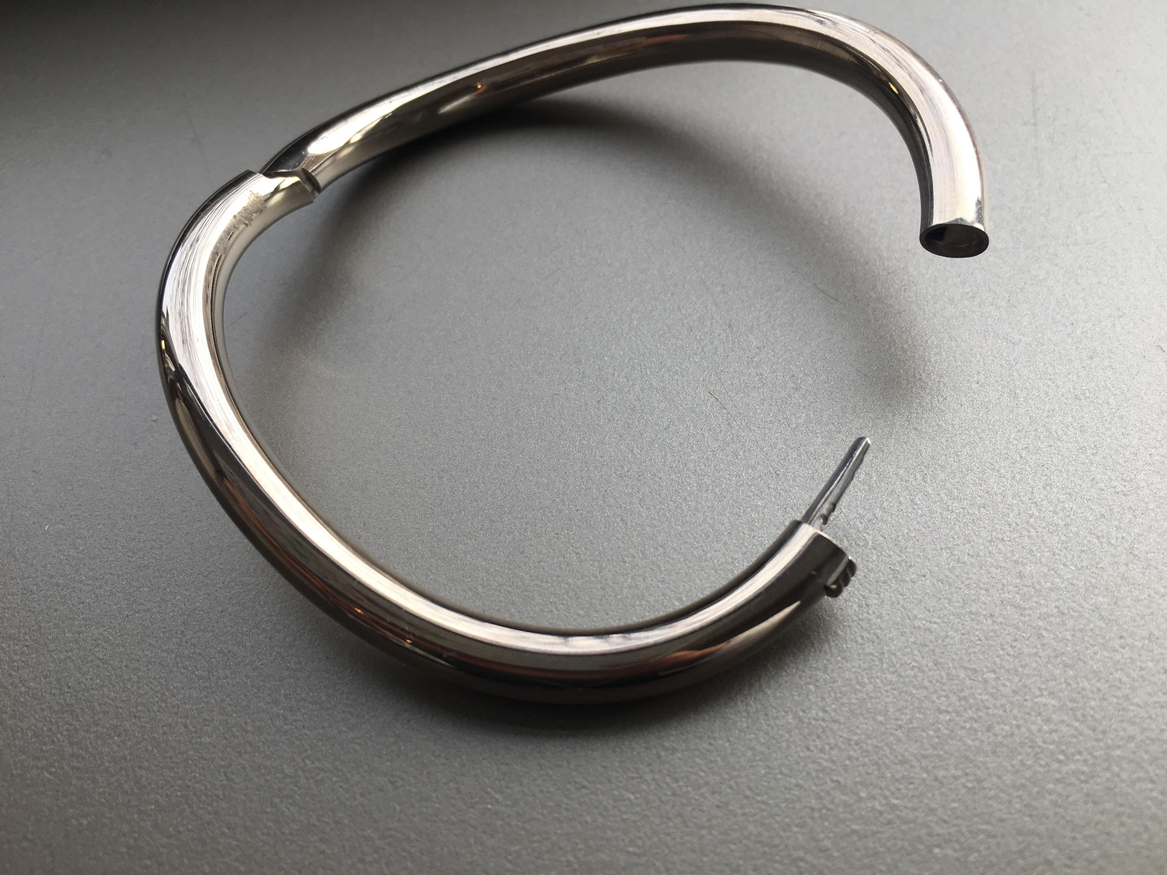 A contemporary design bangle in 18 karat white gold with a wave design.

A simple yet elegant bracelet made with utmost precision in Germany.  The handmade catch is almost invisible and very secure.  This sleek contemporary bangle will complement