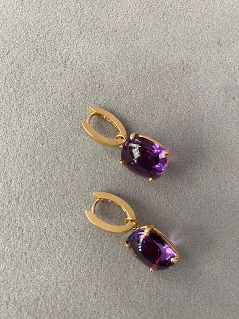 Regal purple Amethyst drop earrings which perfectly frame your profile. The movement of the exceptionally sized amethysts shows flashes of the vibrant spectrum of colour. Features an unusual buff top cut with the facets at the bottom of the