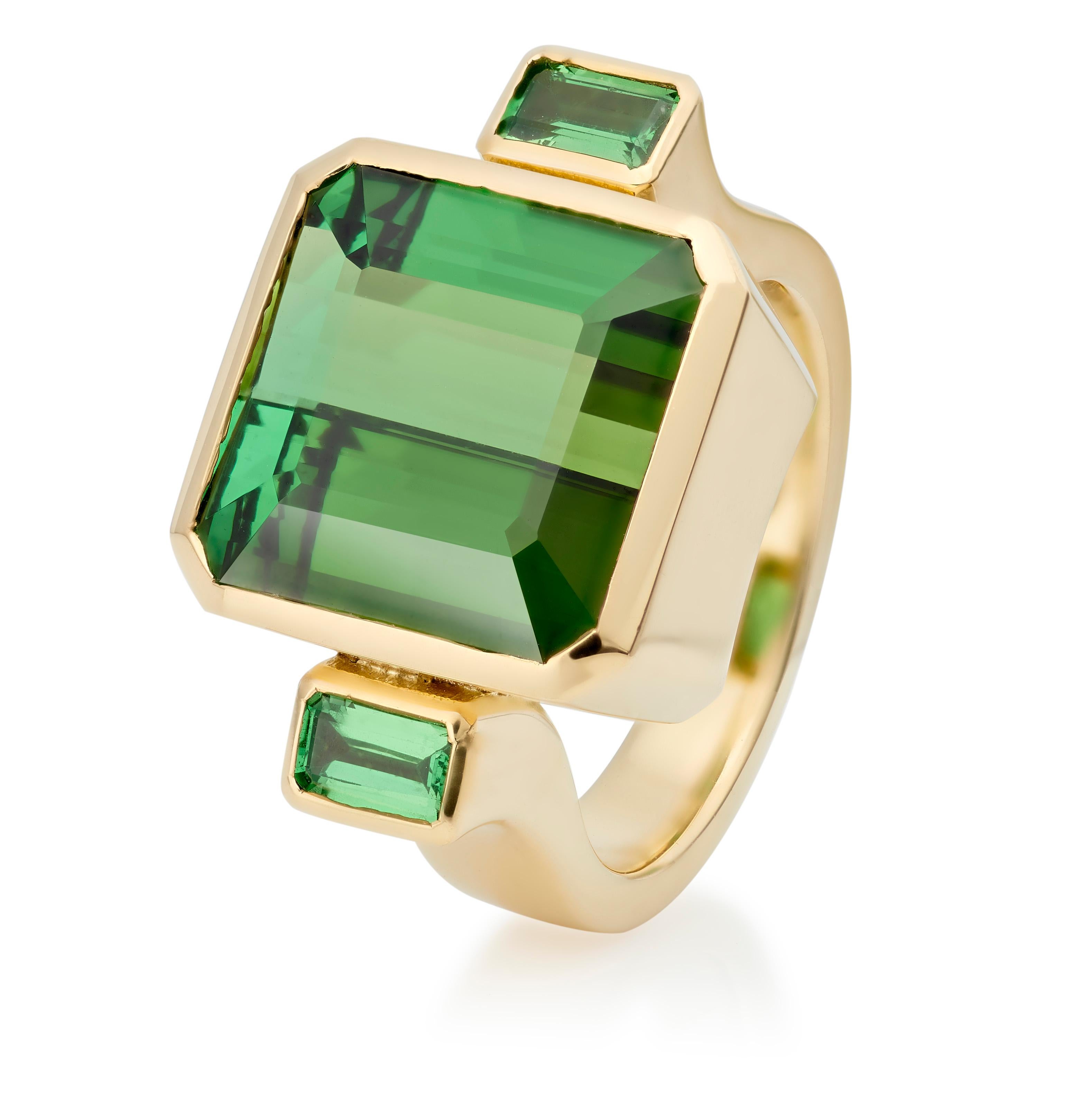 The Bon Bon Ring is one of Lilly Hastedt's signature rings. The design on this ring follows the squareness of the gemstones.  The central green Tourmaline is a huge stone weighing 11.56 cts. and is paired with a pair of sparkling baguette Tsavorite