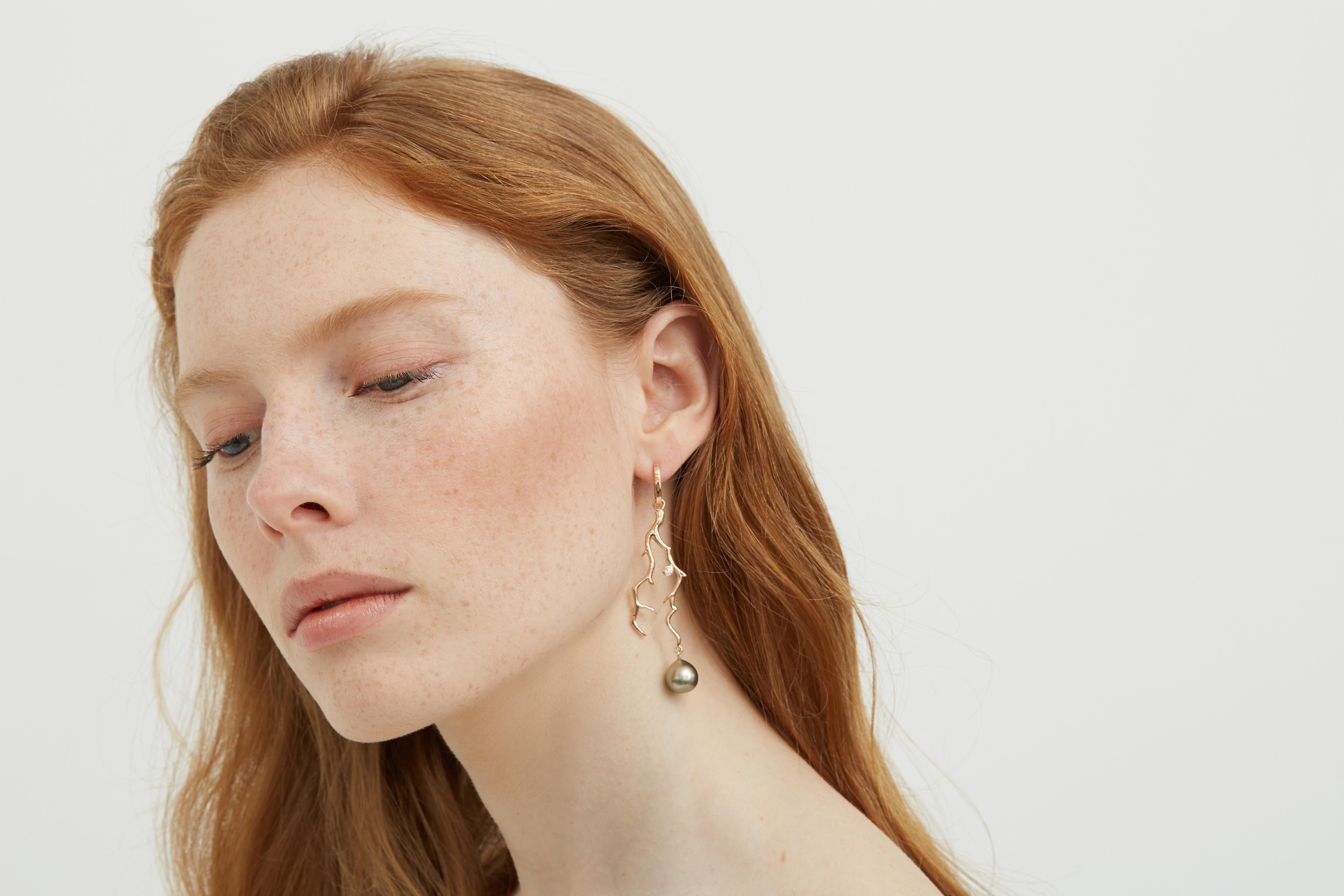 A striking pair of long coral branch inspired earrings with grey Tahitian pearls, and diamonds set in 18 karat rose gold.  The earrings are asymmetric, the left earring with a Tahitian keshi pearl and the right earring with diamond.

The color of
