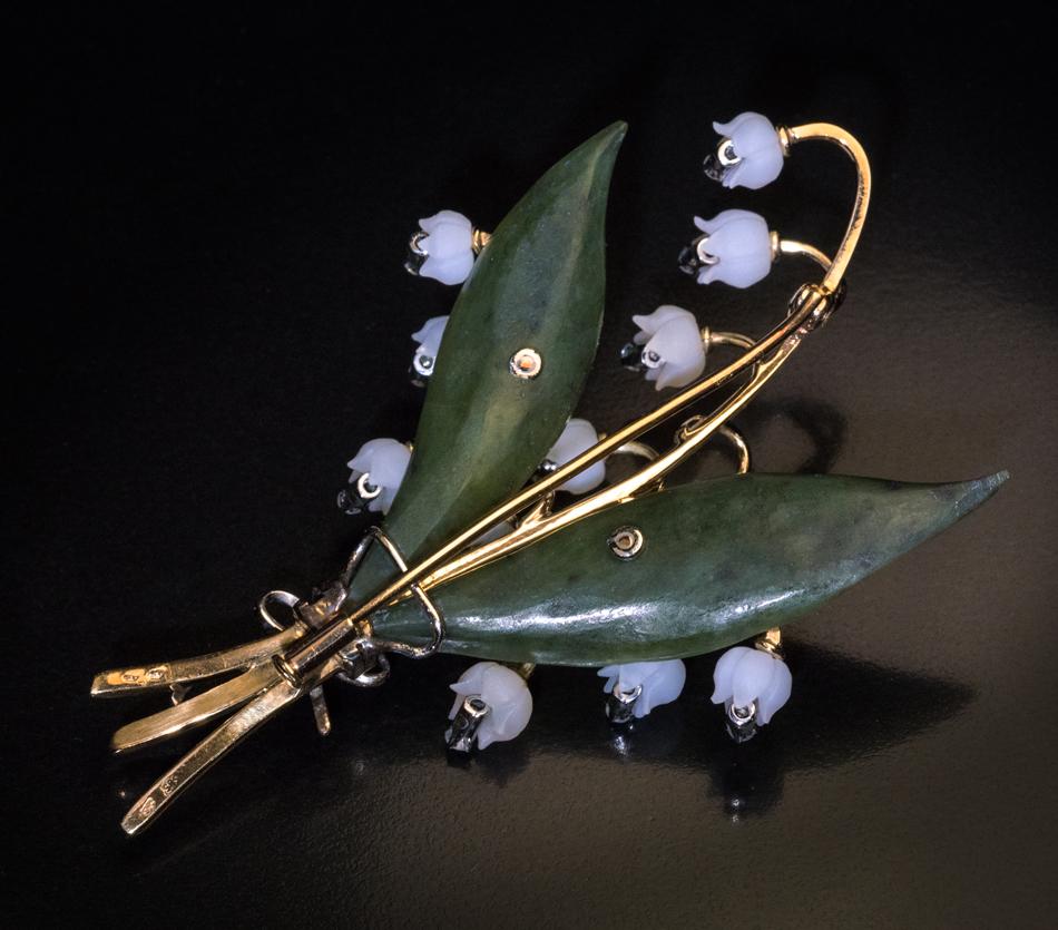 Made in Vienna, Austria in the 1950s.

This vintage brooch / pin is designed as a ribbon-tied spray of lilies of the valley. The hand carved nephite leaves and rock crystal flower heads are mounted in 14K yellow and white gold. Each flower head is