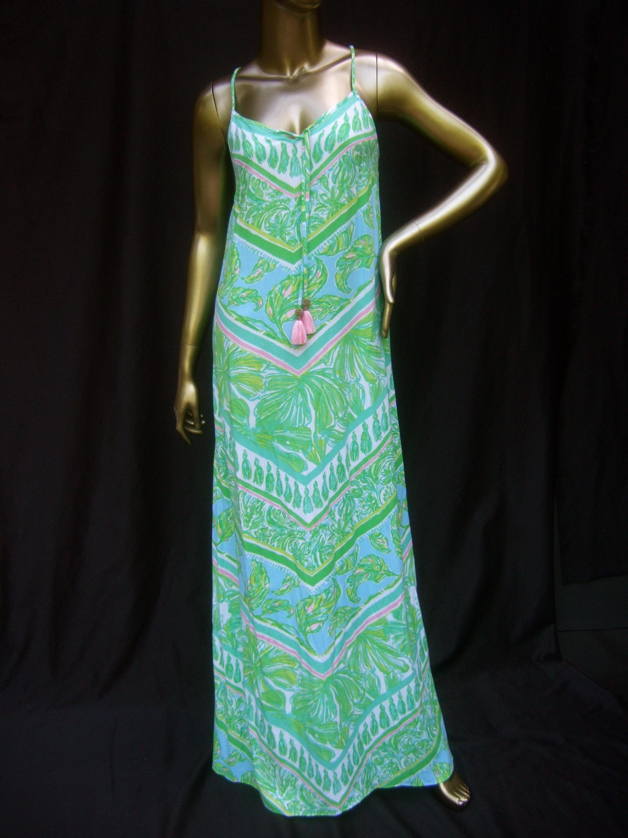 Lilly Pulitzer Vibrant tropical print slip gown. Size Extra Small 
The bold print spaghetti strap rayon gown is illustrated 
with lush lime green foliage with aqua blue & pink accent
colors

Adorned with a pair of pink copper beaded fringe tassels 