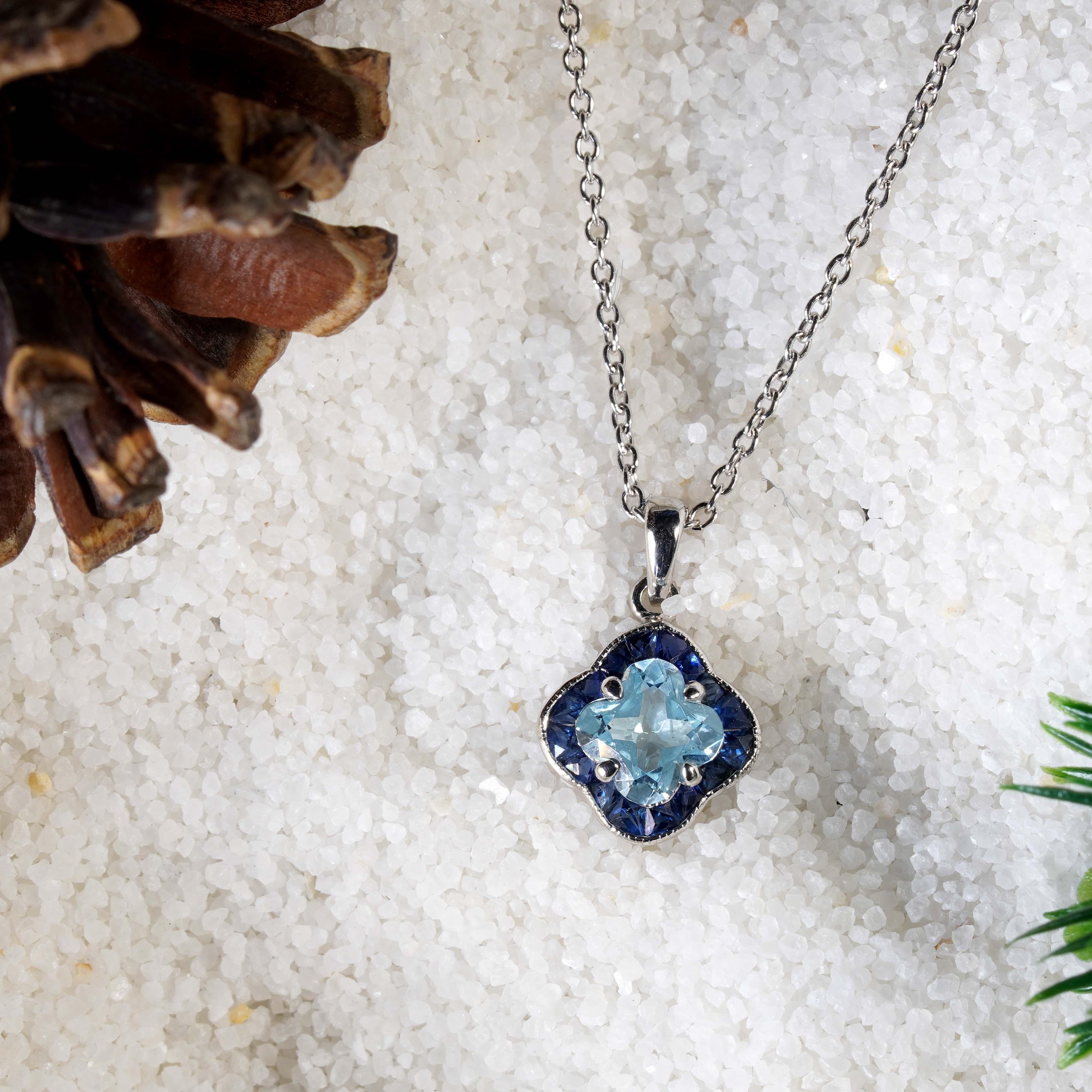 Sophistiqué et élégant, ce collier à pendentifs design s'inspire de la beauté de la fleur de lys gelée. La pierre centrale, une topaze bleue brillante taillée en Lys, représente l'éternité et la jeunesse. Elle est entourée de saphirs taillés en