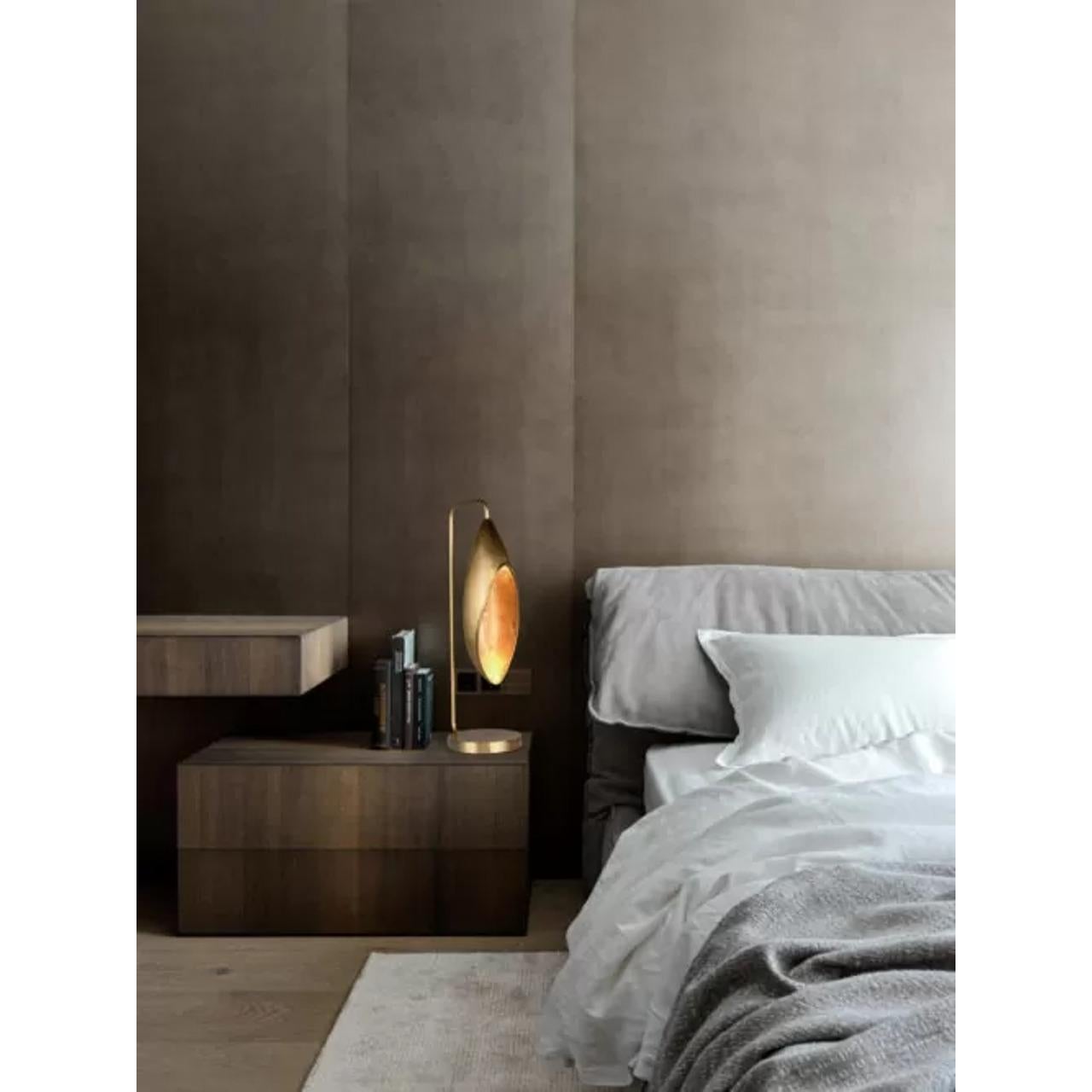 La lampe à poser Lily de la Collection Sols incarne l'élégance et la beauté de la fleur de lys à travers son design minimaliste et moderne. Fabriqué en laiton texturé et en cristal, le corps de cette lampe imite gracieusement la silhouette naturelle