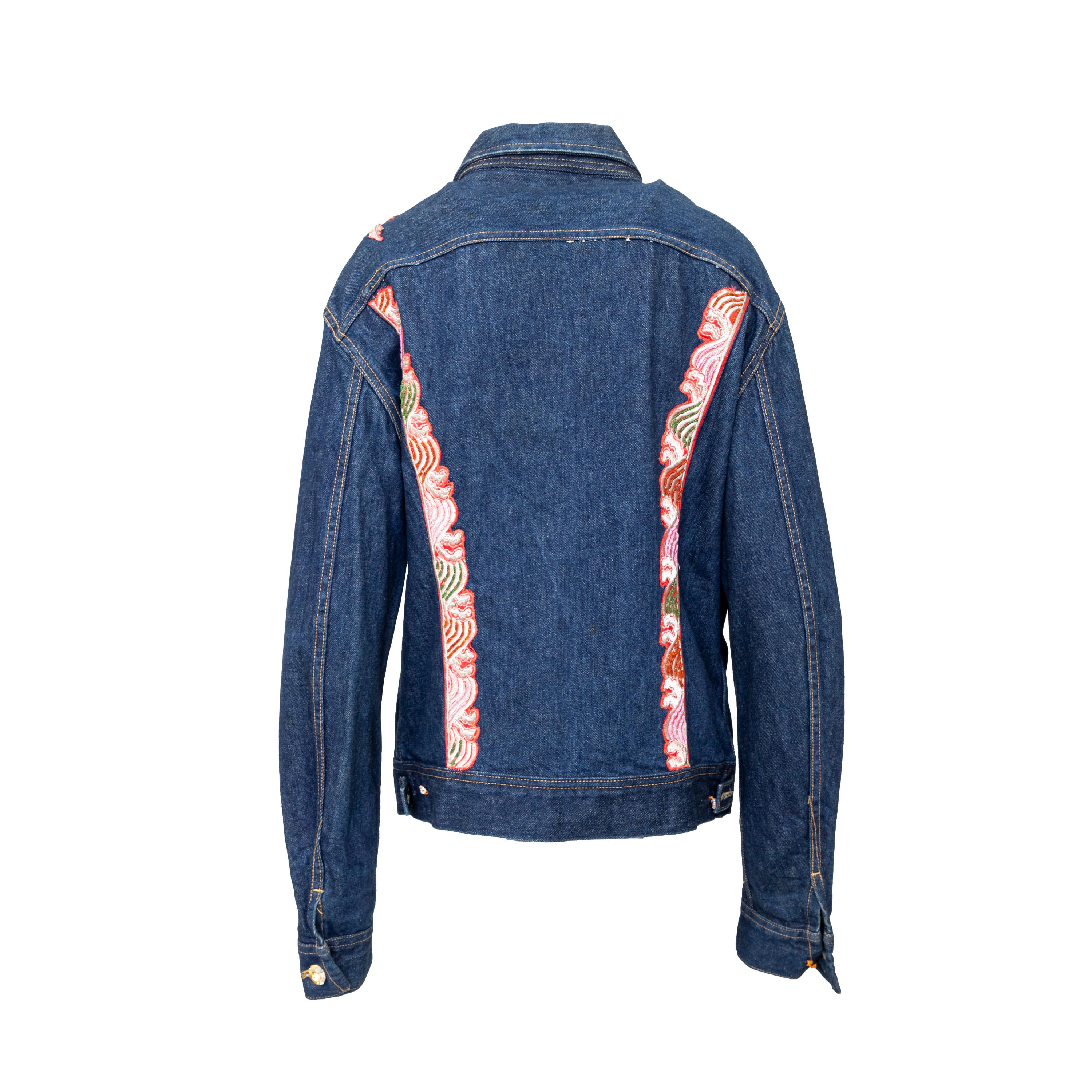 This Lily Farouche Munich denim jacket adds a playful touch to any outfit. Crafted with dark blue denim, long sleeves, and central buttoning with jewel buttons, this garment features a multicoloured floral appliqué embroidery decorated with sequins