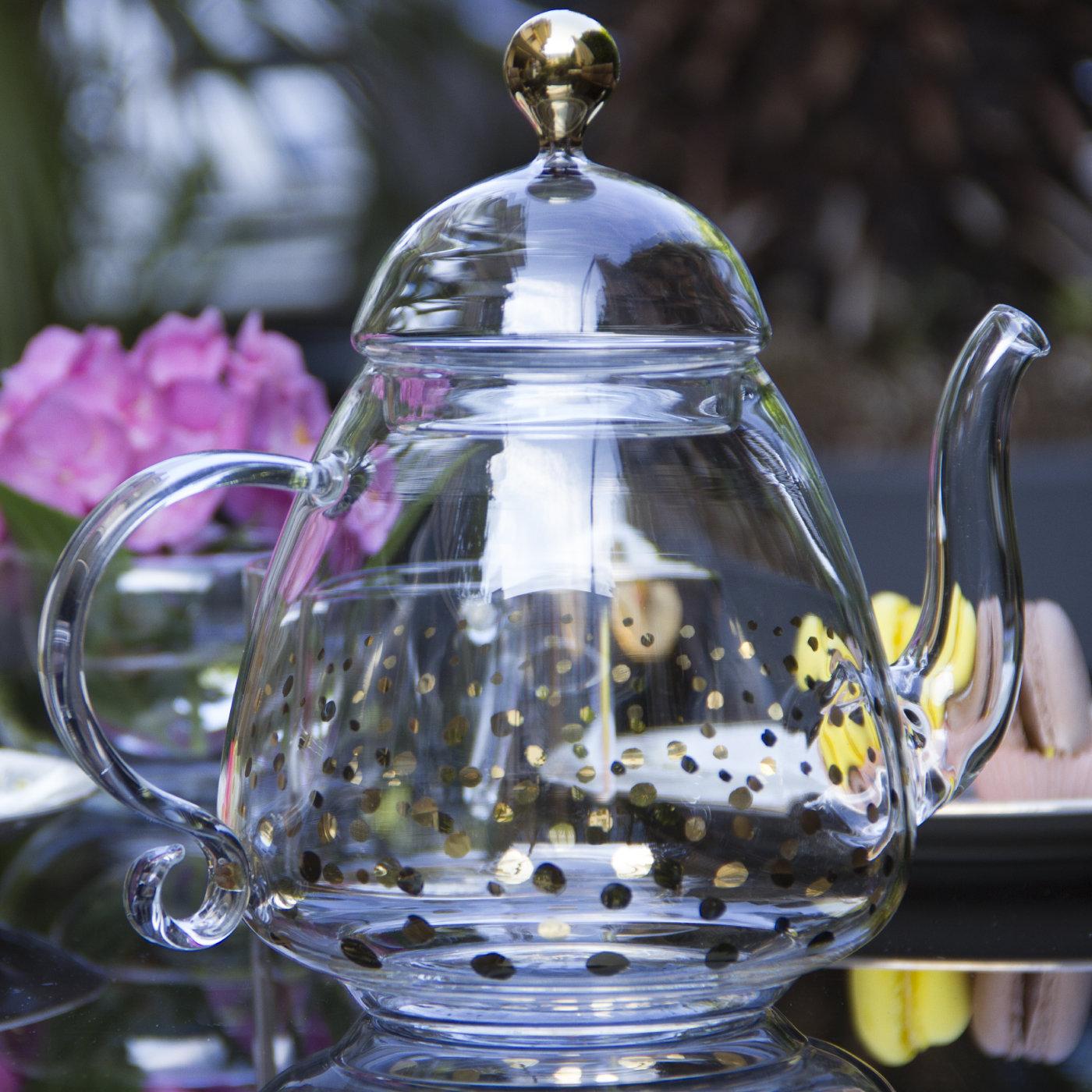 This stunning teapot is sure to make a sophisticated statement on any occasion. It was crafted of handmade mouth-blown transparent glass and features a traditional shape with a sinuous bottom, an upward spout, a curved handle with a curl, and a
