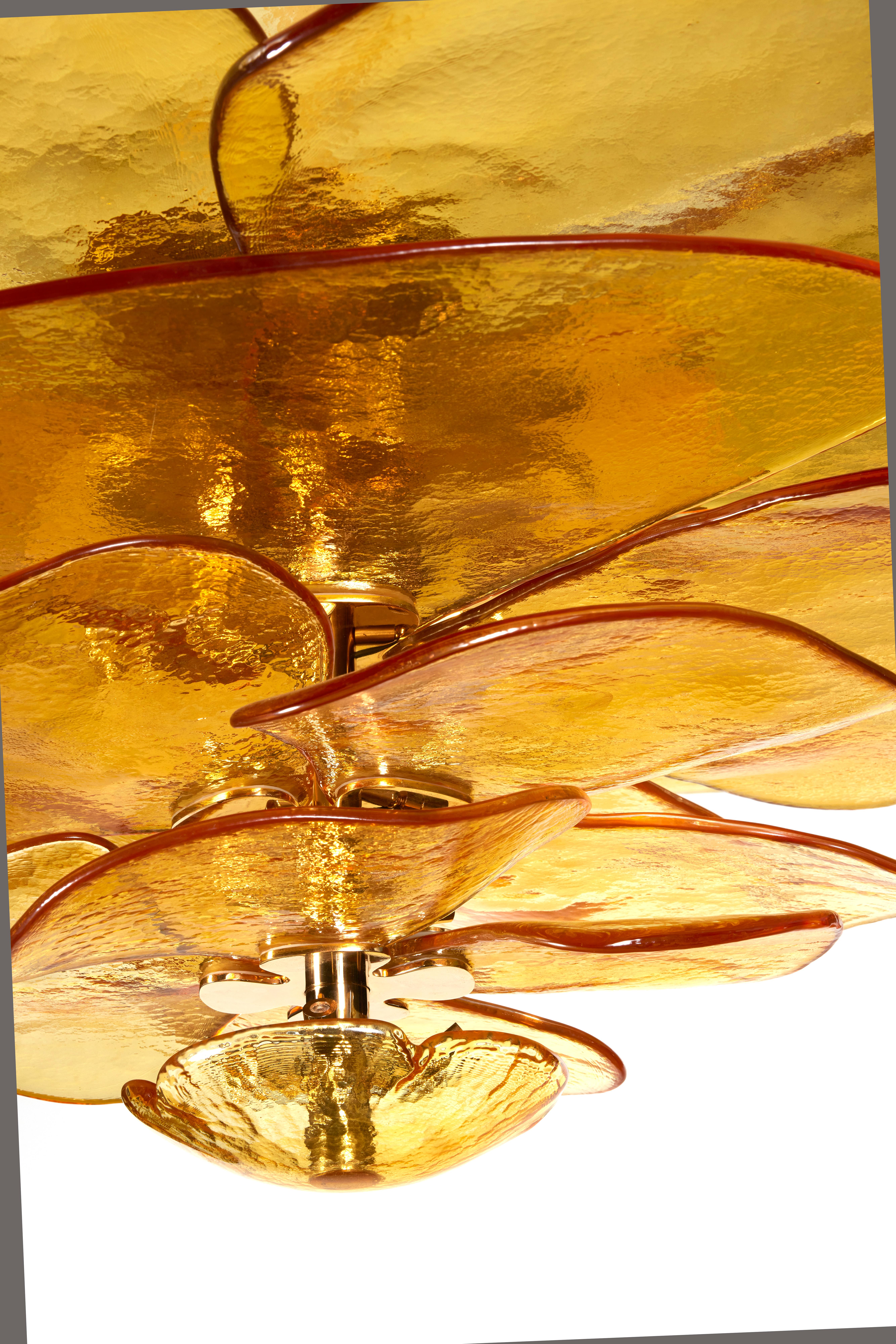Lustre en verre texturé composé de pétales individuels ambrés montés sur une structure en laiton, en forme de fleur de nénuphar qui diffuse la lumière. 
Le lustre est composé de 24 spots.
Tout est fabriqué dans le nord de l'Italie, près de Venise.