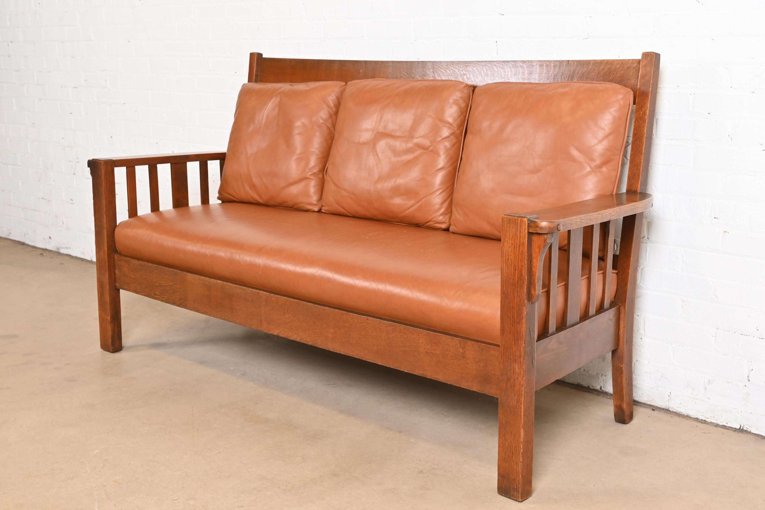 Un precioso sofá, banco, diván o love seat antiguo de la época Mission o Arts & Crafts

A la manera de Charles P. Limbert Co.

EE.UU., Circa 1900

Armazón de roble aserrado en cuarto, con tapicería de cuero.

Medidas: 71,75