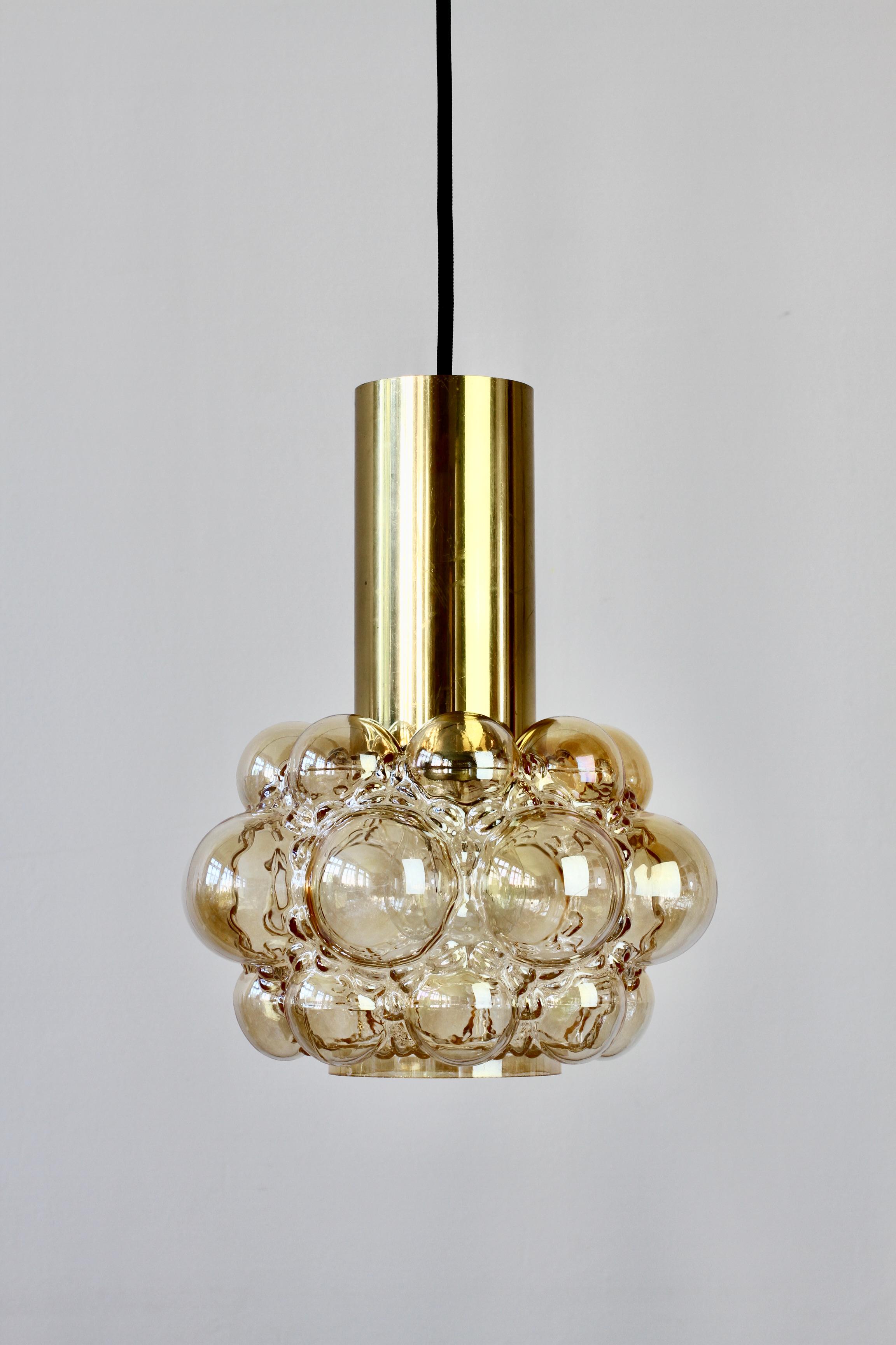 Late 1960s petite bubble glass ceiling pendant light designed by Helena Tynell for Glashütte Limburg. The light features a beautiful lampshade made from amber or champagne colored / coloured glass with a polished brass cylinder on top.

This,