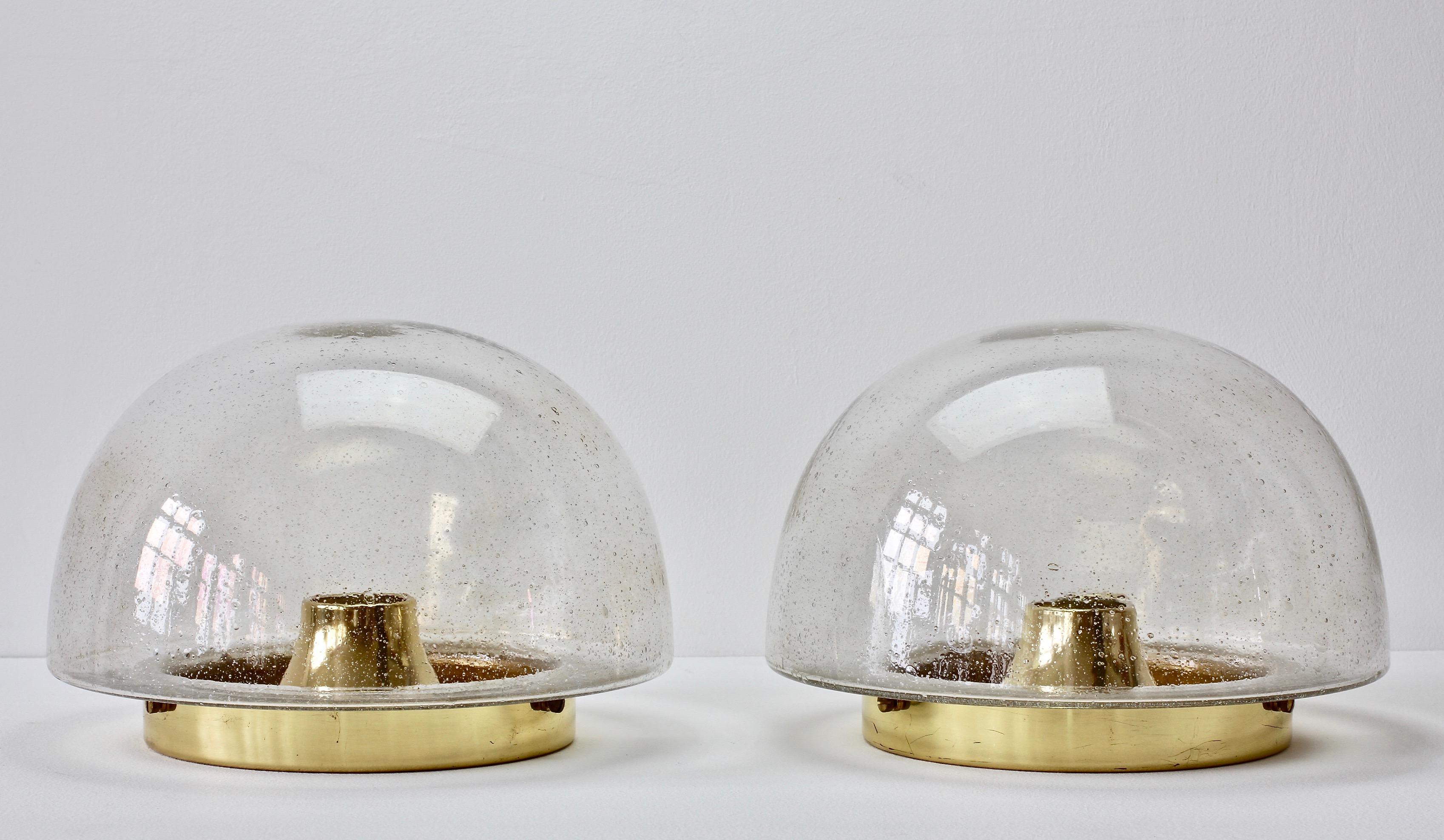 German made late Mid-Century Modern wall or ceiling flush mount lights produced by Glashütte Limburg, circa 1975. Featuring a round domed mouth blown bubble glass shade and a polished brass mount. Being mouth blown each piece of glass represents a