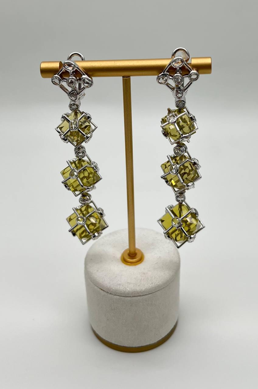 Questi orecchini contemporanei presentano una serie di quarzi gialli geometrici del peso di 86 carati, ciascuno incastonato in una struttura a reticolo in oro bianco 18 carati. Il design presenta tre quarzi gialli lemon quadrati per orecchino,