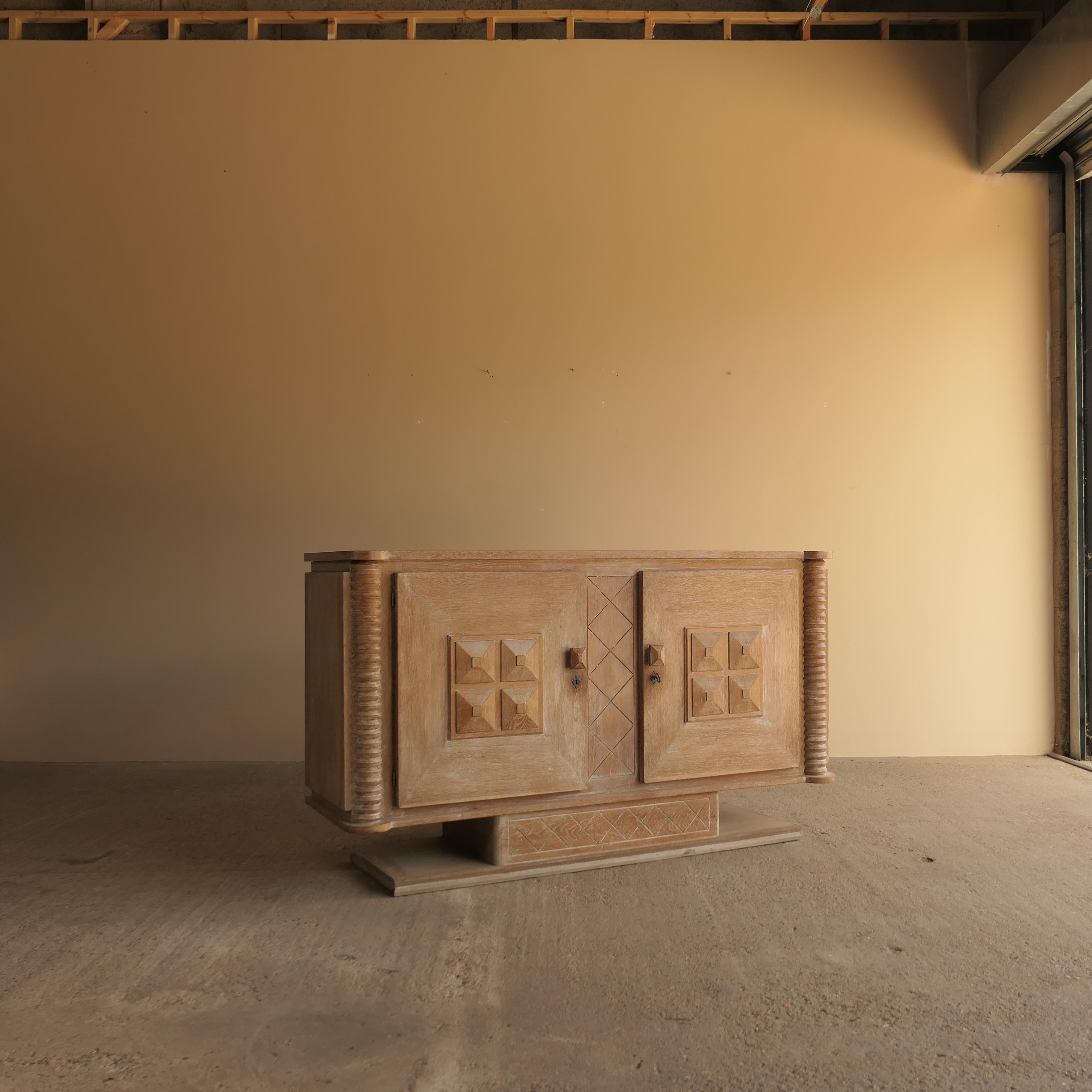 Este excepcional aparador francés fue diseñado por el célebre diseñador de mediados del siglo XX Charles Dudouyt en la década de 1940. Fabricada en madera maciza y acabada con una chapa de roble blanqueado de bella textura, la pieza presenta tallas
