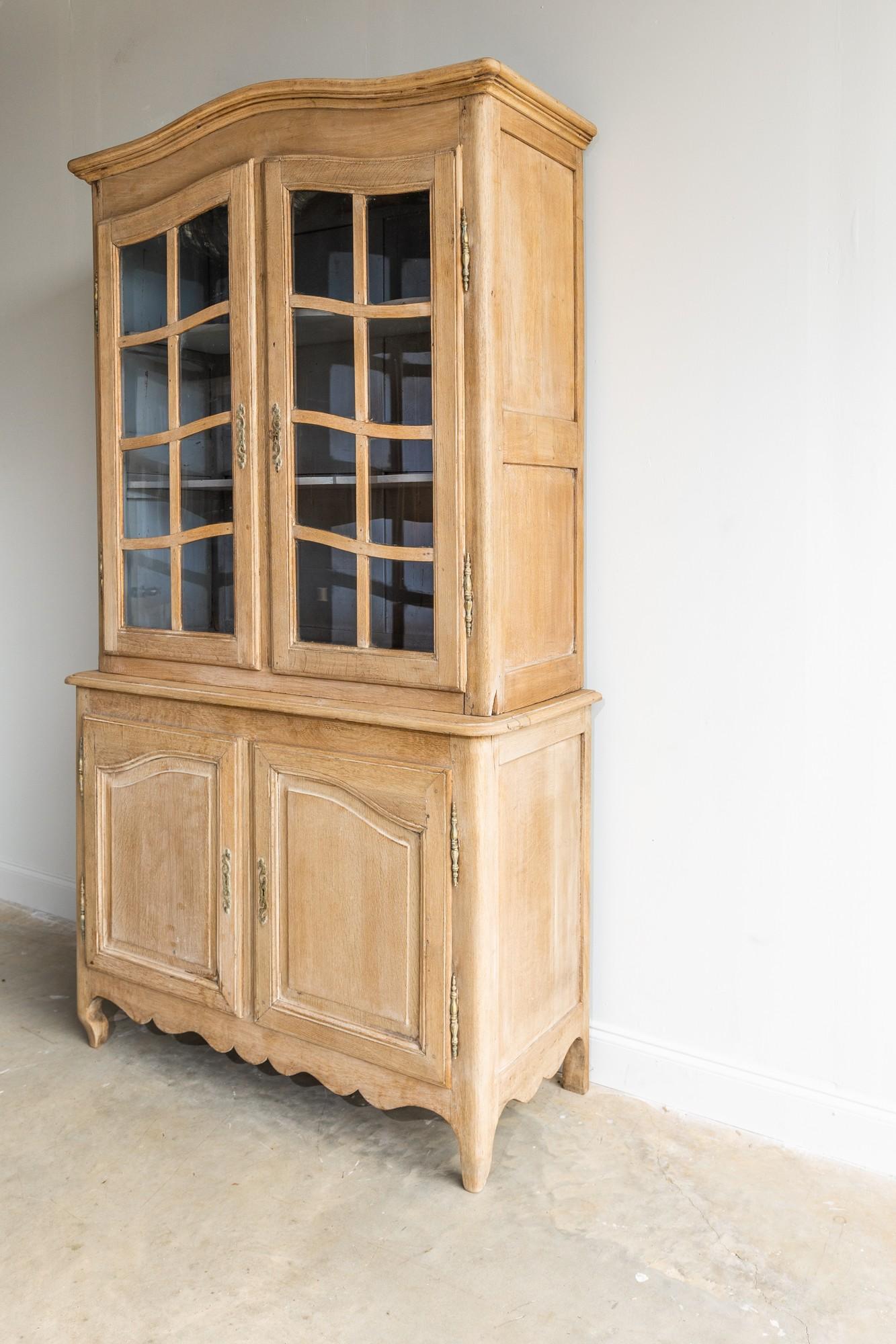 This beautiful limed walnut buffet deux corps originates from 20th century England. The original glass cabinet doors have an upward curve detail that add so much uniqueness to this piece. The original hardware and key all work properly. The bottom