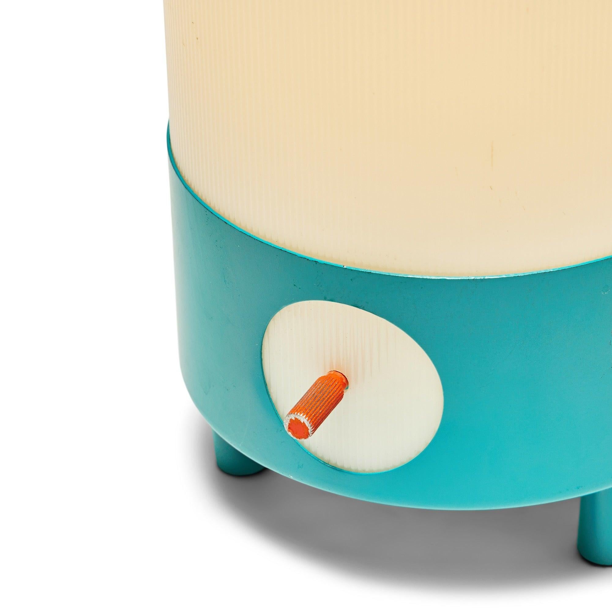 A cylindrical table lamp with a turquoise base. It's wired for a 3-way switch for varying brightness levels.