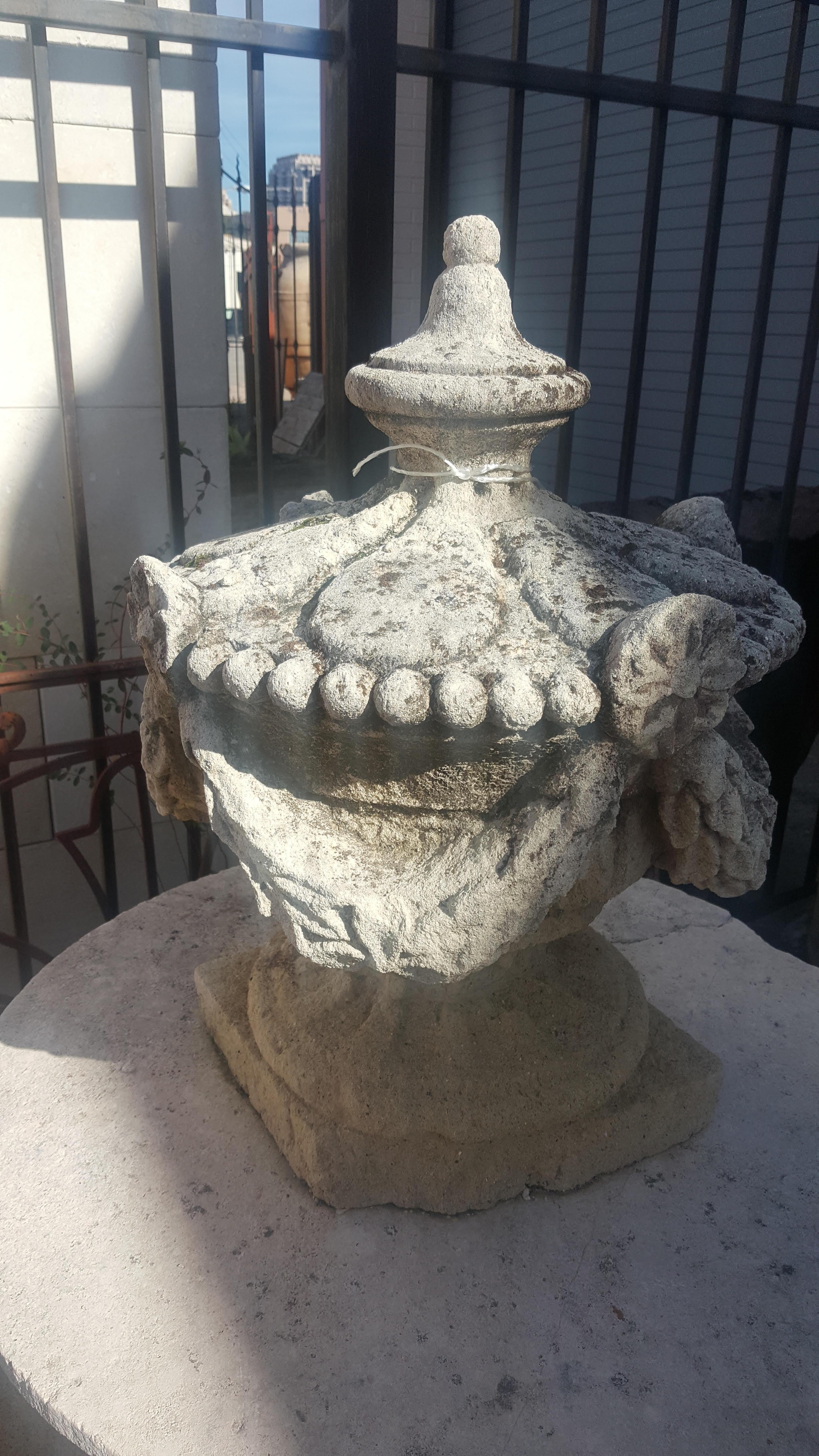 Limestone garden decor with a gadroon, flower, and swag design.