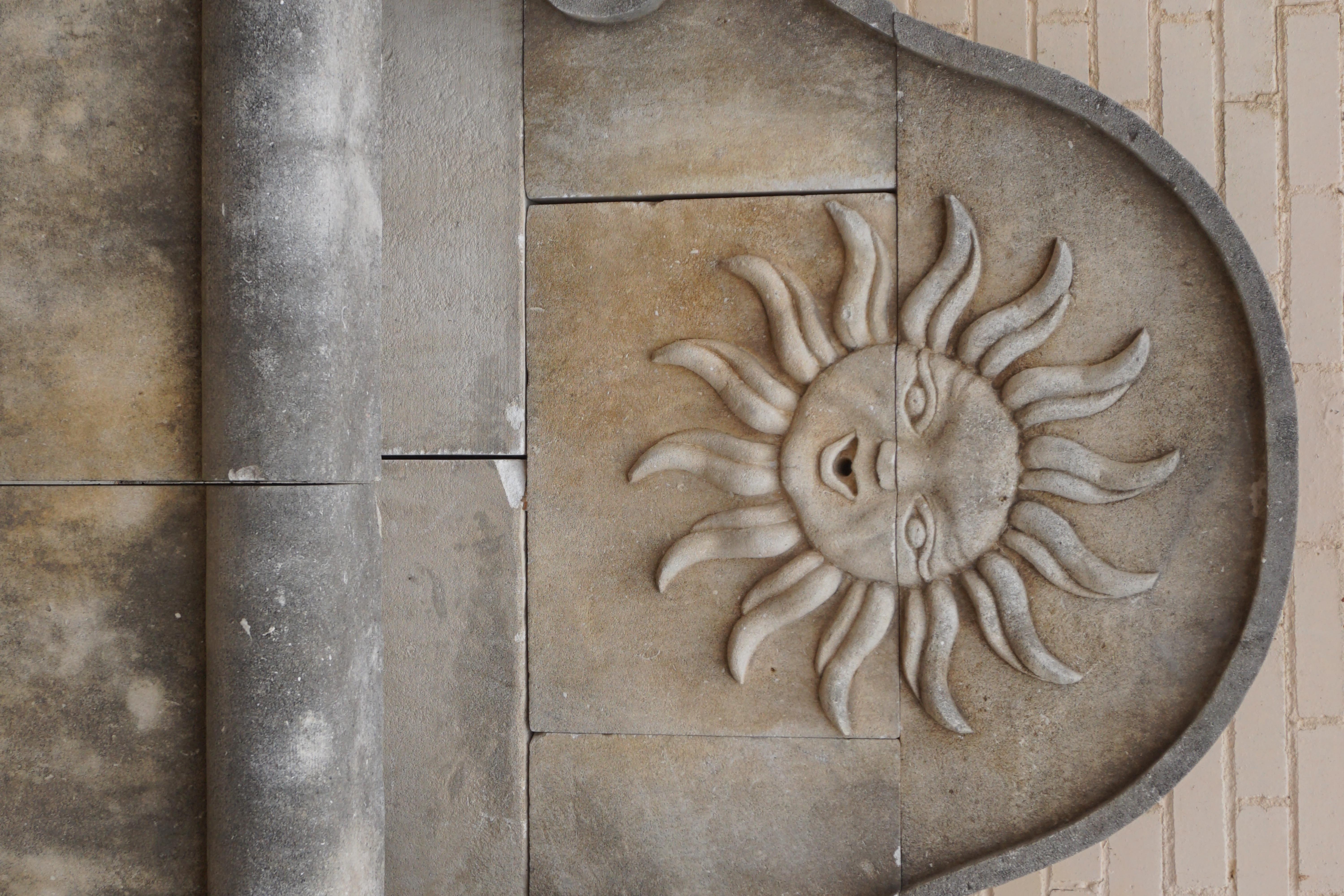 Here we offer a hand carved limestone wall fountain with a carving of the Sun with a human face. Louis XIV chose the sun as his emblem. The sun was associated with Apollo, god of peace and arts, and was also the heavenly body which gave life to all