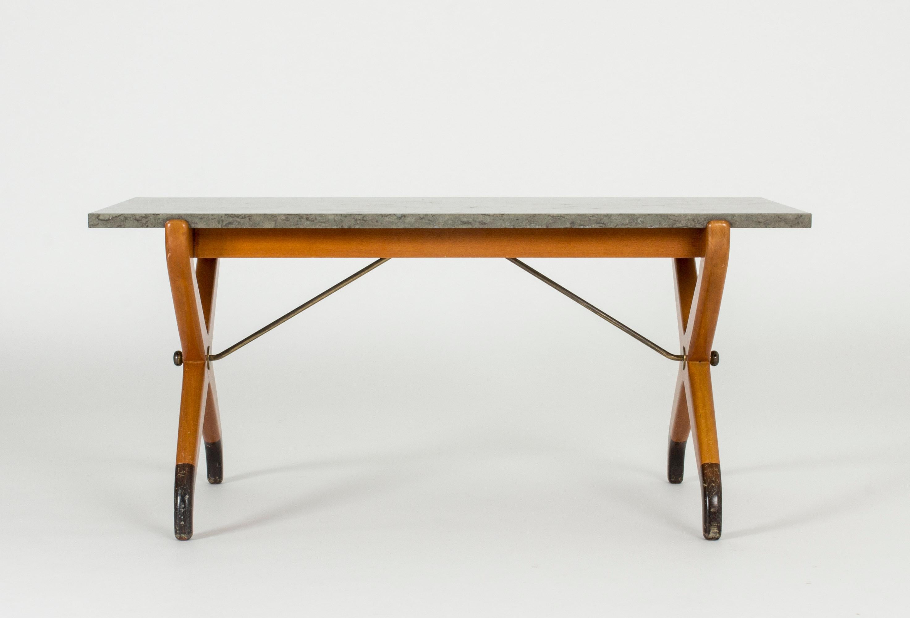 Amazing coffee table by David Rosén from the “Futura” furniture series. Beech base with crossed legs and brass extenders. Thick, heavy limestone tabletop.