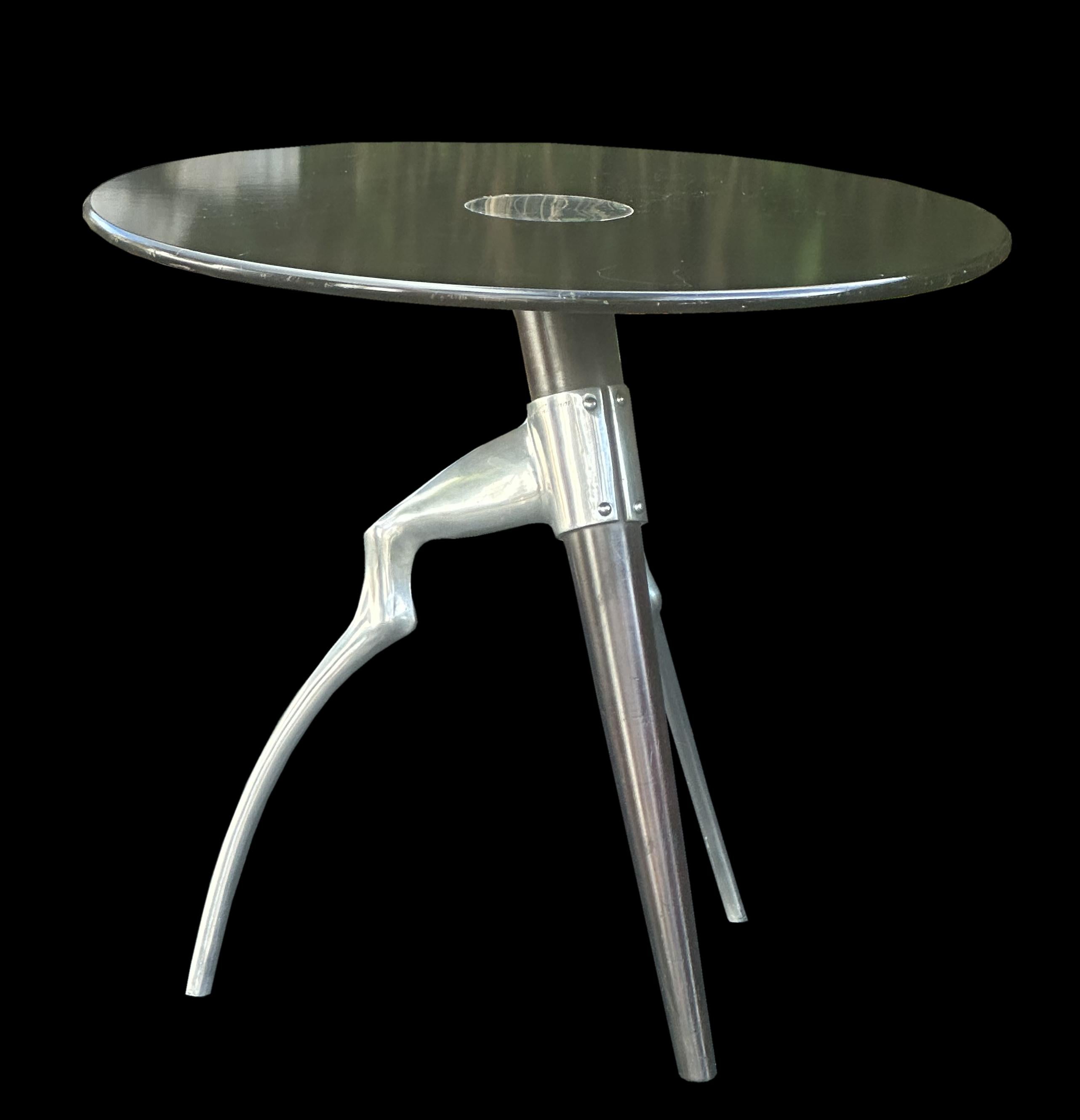 This is number 139 from a limited edition, and with engraved signature of the designer, this antelope table has an stained and polished MDF circular top which has an inlaid staiinless steel disc in the center, the single stained Sycamore leg havin