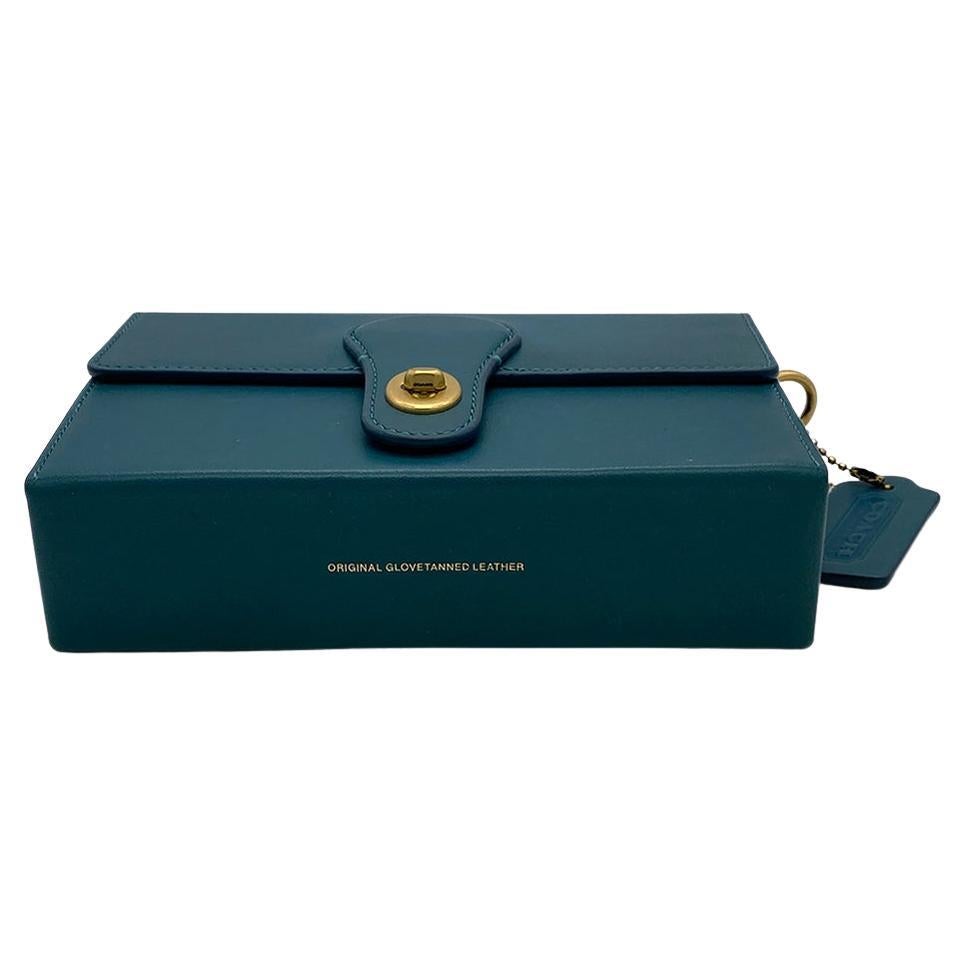 This is a limited edition Coach glovetanned leather box clutch with a brass turn or twist closure. It's part of Coach's special collection of archival Coach silhouettes remade for now with the finest leather inside and out. The amazing peacock blue