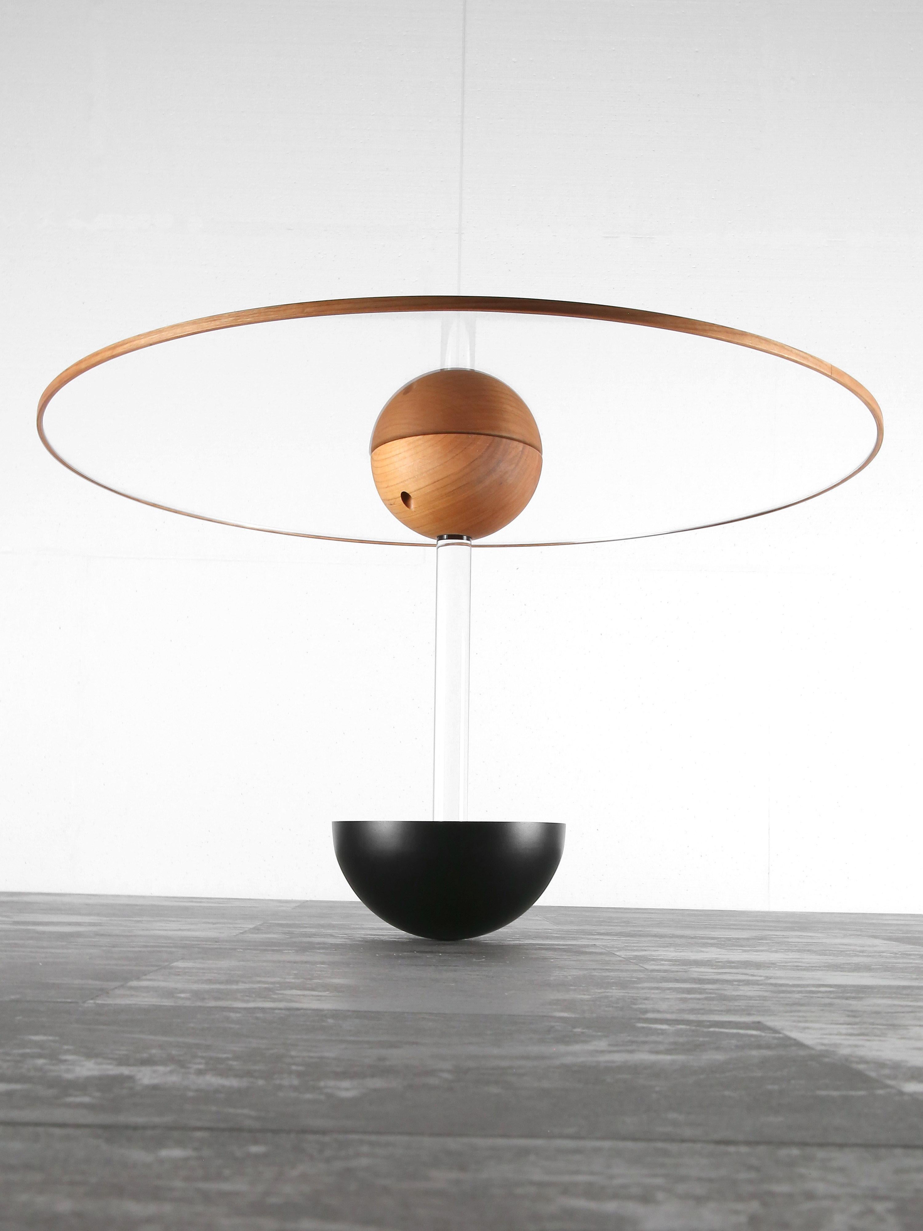 Coffee table BalanceTable is made of acrylic glass, solid cherry wood and two hemispheres, one of lacquered steel at the bottom and one of lacquered aluminium at the ceiling. 

This item plays with gravity by standing only on the pole of the lower