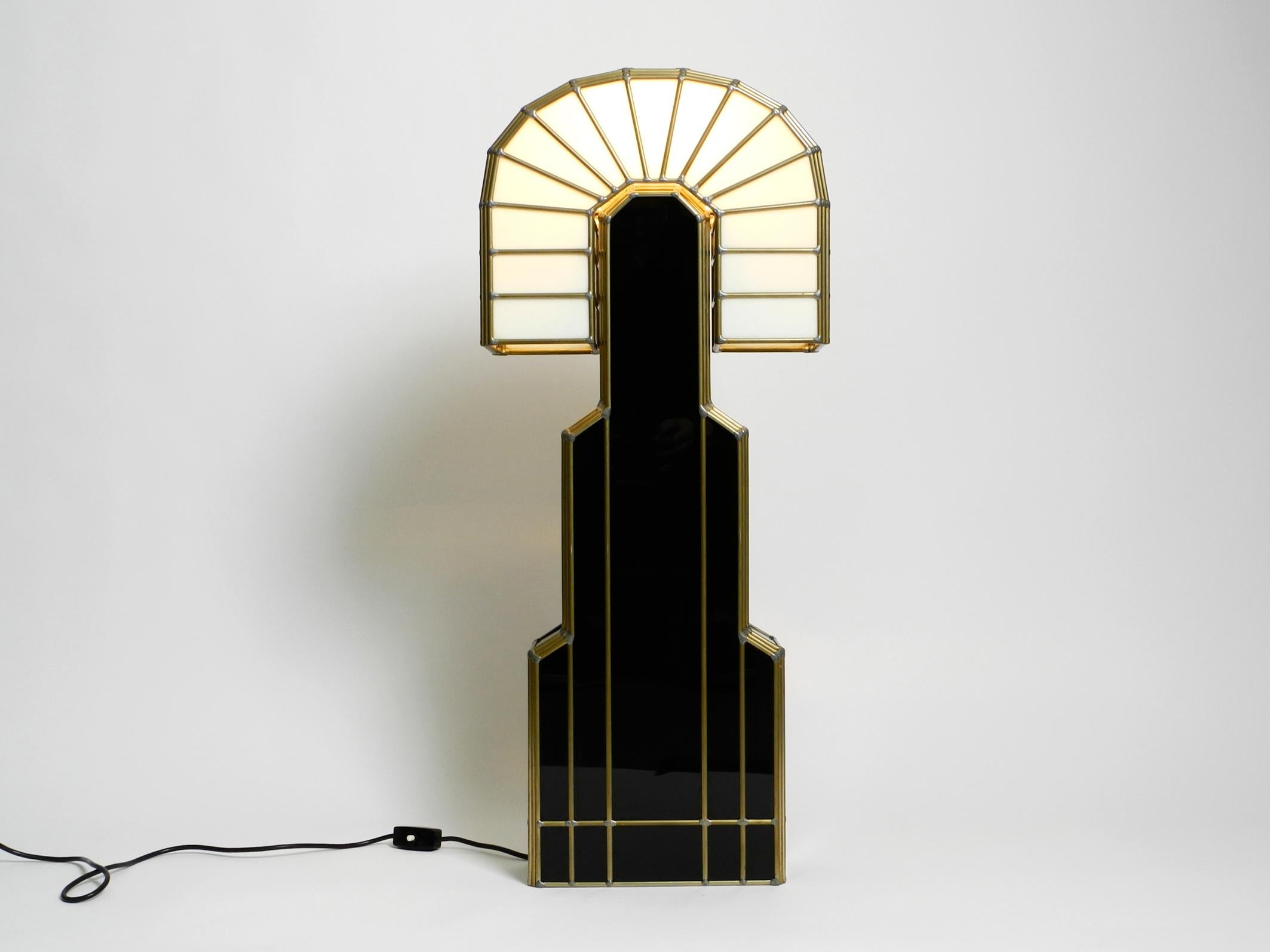 Very extraordinary, huge, beautiful Postmodern Art Deco Tiffany Design table or floor lamp from 1980.
Design by Schulz, with original label at the bottom edge.
Limited to 100 pieces. This is number 15.
Frame consists of black glass and