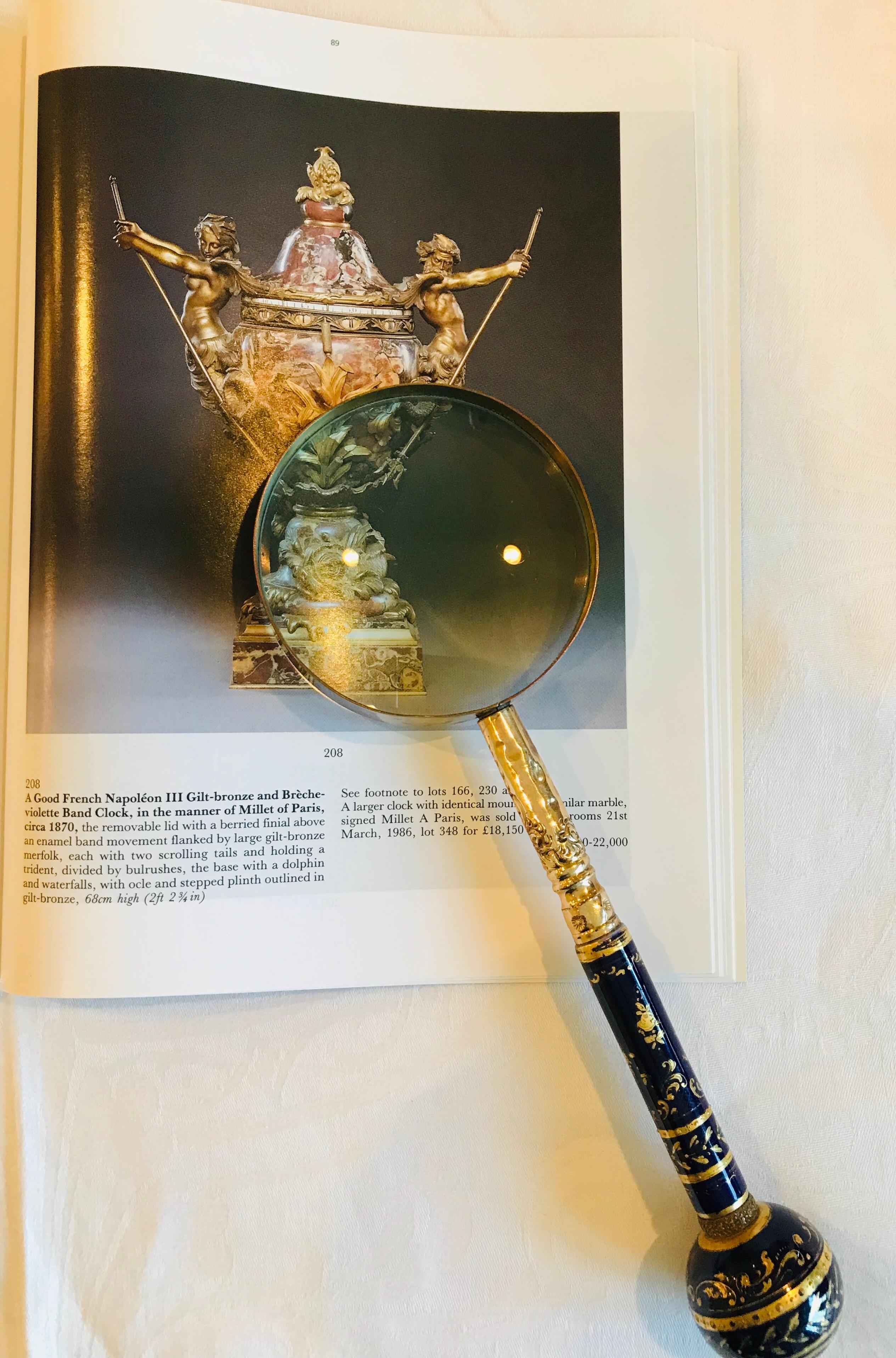 Produced in Limoges, France during the Belle Époque, this cobalt porcelain magnifying glass is heavily encrusted with a raised gold design depicting abstract arabesques and flowers. 

Personalized for the buyer, the round bulb at the end of the