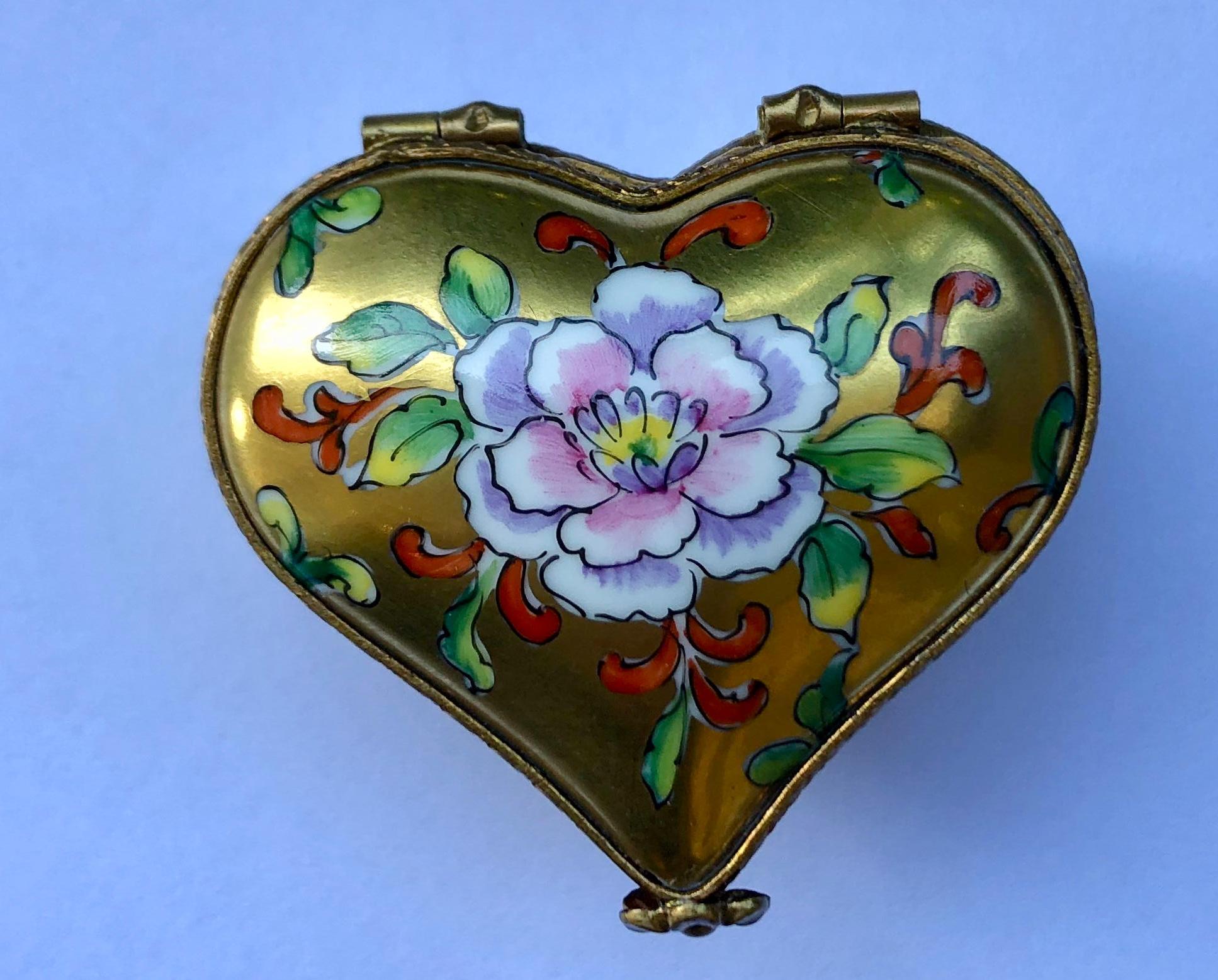 Collectible handmade and hand painted Limoges porcelain miniature heart shaped trinket box features an opulent 24 karat gold exterior decorated with an exquisitely detailed and colorful stylized floral motif design, gold gilt metal fittings and a