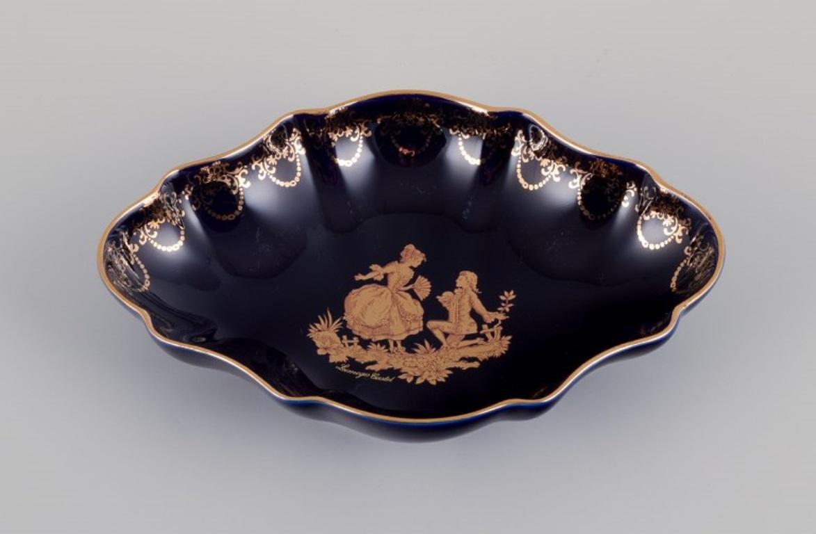 Limoges, France. Bol et deux petits plateaux en porcelaine 
Décoré de feuilles d'or 22 carats et d'une magnifique glaçure bleu royal. Scène galante. 
Environ à partir de 1970.
Provenance : D'une grande collection privée française de porcelaine de
