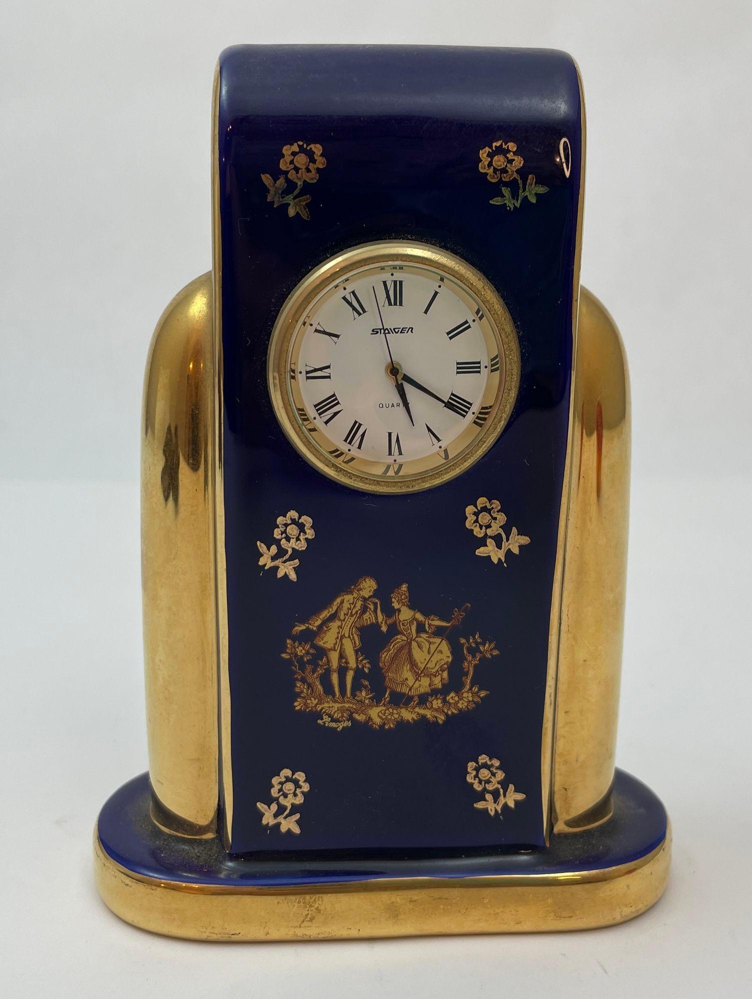 Limoges France Porcelain Imperial Blue Cobalt Battery Operated Desk Clock Vintage Limoges gilded French cobalt blue porcelain clock featuring a beautiful scene of lovers courting done in 22kt gold.
There is hand painted gold floral around the top