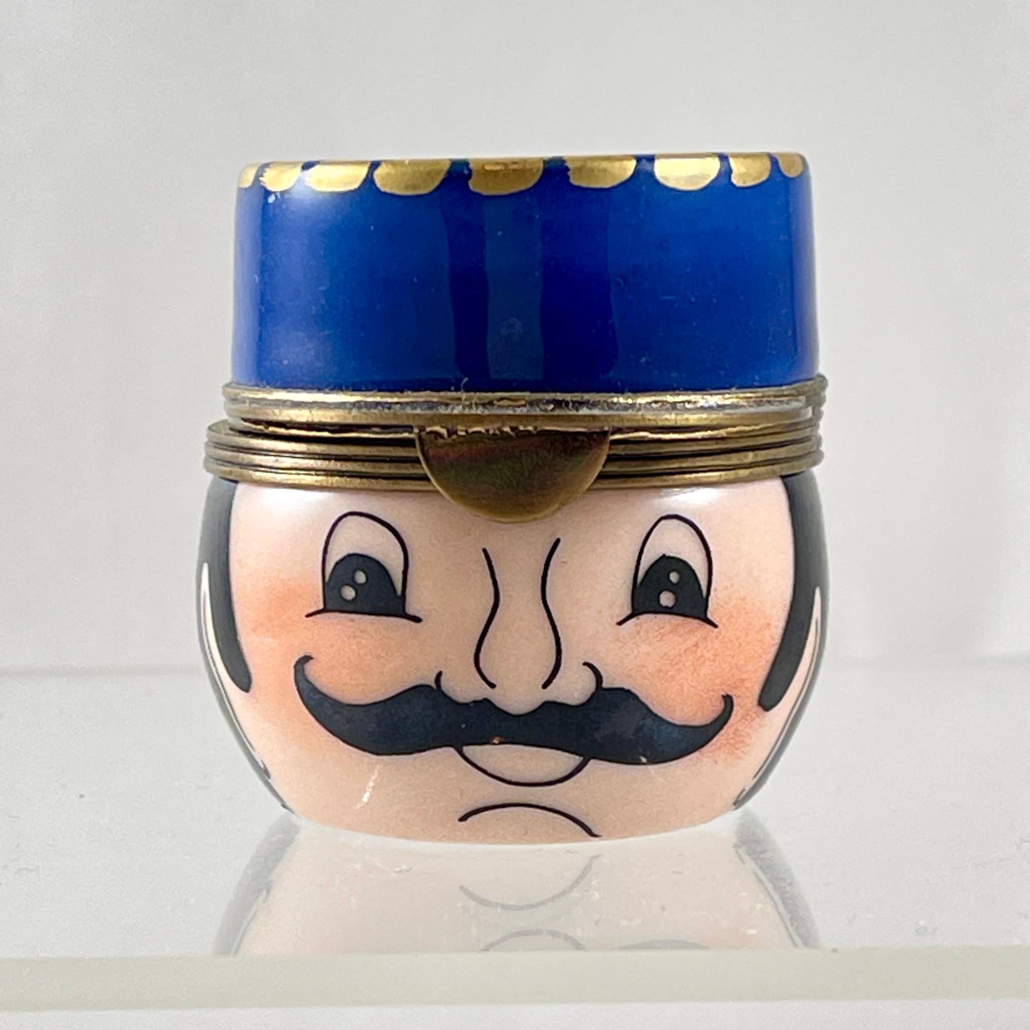 De Limoges, Francia, una caja de baratijas esmaltada a mano, que representa la cabeza de un gendarme o policía francés, hacia la década de 1970-1980.

Las cajas de Gendarmes son muy buscadas por los coleccionistas.

La oficina lleva el sombrero azul