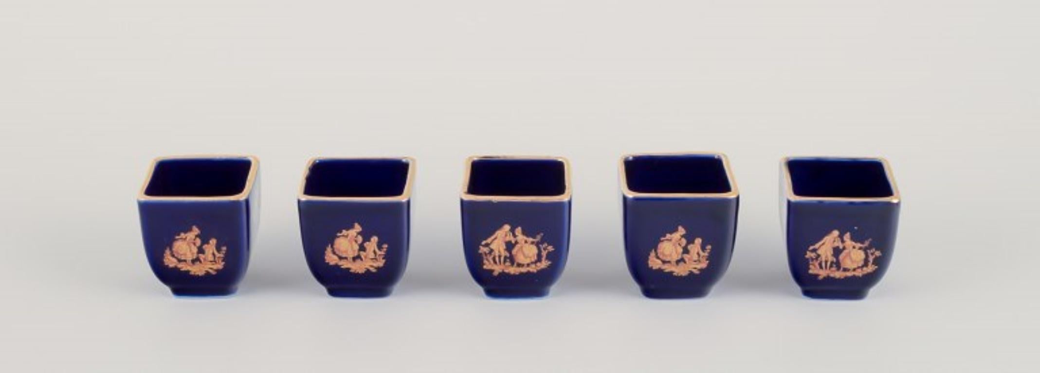 Limoges, France. Cinq vases miniatures en porcelaine décorés de feuilles d'or 22 carats et d'une belle glaçure bleu royal. Scène galante. 
Vers 1970.
Provenance : D'une grande collection privée française de porcelaine de Limoges.
Marqué.
En parfait