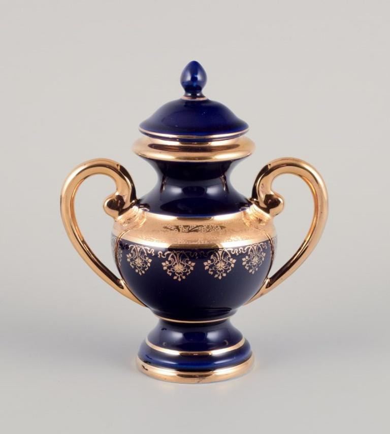 Limoges, France. Five pieces of porcelain consisting of a lidded jar, two vases, a lidded three-footed jar, and a dealer advertising sign.
Decorated with 22-karat gold leaf. Beautiful royal blue glaze. 
Scène galante. 
Approximately