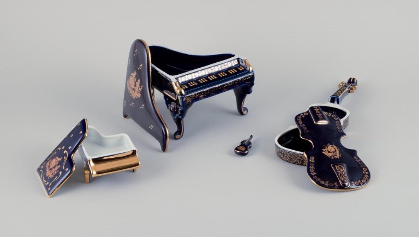 Limoges, Francia. Cuatro instrumentos musicales de porcelana decorados con pan de oro de 22 quilates y bello vidriado azul real. Escena galante. 
Aproximadamente 1970.
Procedencia: Procedente de una gran colección privada francesa de porcelana de