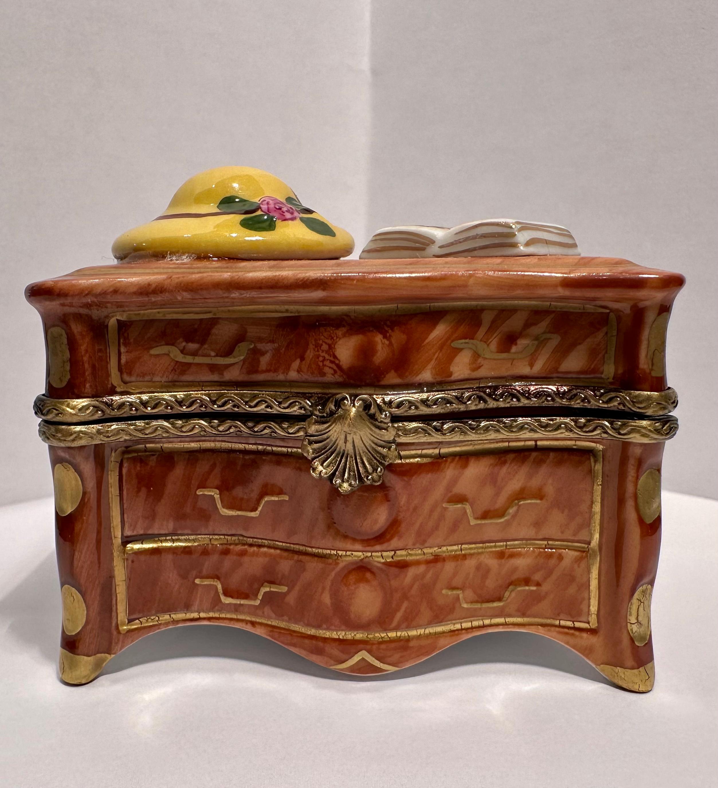 Collectible and very unique, Limoges porcelain miniature trinket box is handmade and hand painted in France and features a very detailed wood grain dresser with hand painted handles and paneled sides on cabriole legs.  The fancy antique gold gilt