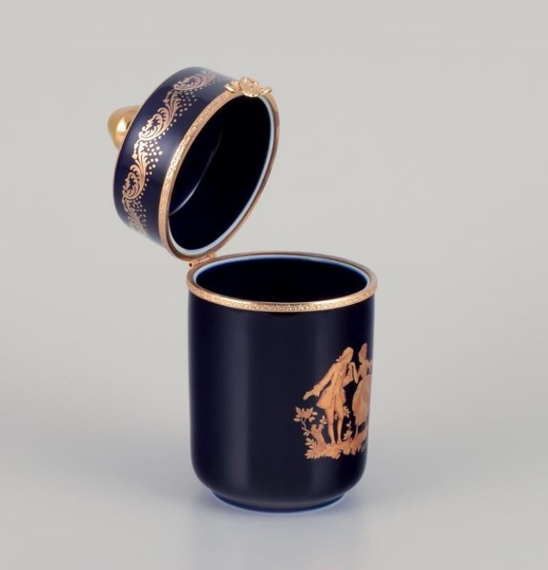 Limoges, Francia. Caja de porcelana con tapa y monturas de latón. 
Adornada con pan de oro de 22 quilates y con un precioso esmalte azul real con una Scène galante.
Aproximadamente 1970.
Procedencia: Procedente de una gran colección privada francesa