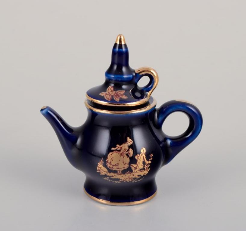 Limoges, France. Miniature porcelain set consisting of a cup, teapot, two pitchers, and a tray. Decorated with 22-karat gold leaf and beautiful royal blue glaze. Scène galante. 
Approximately 1970.
Provenance: From a large French private collection