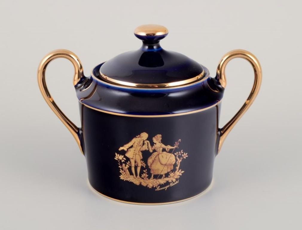 Limoges, France. Une tasse à café en porcelaine avec une soucoupe et un sucrier décorés de feuilles d'or 22 carats et d'une belle glaçure bleu royal. Scène galante. 
Vers 1970.
Provenance : D'une grande collection privée française de porcelaine de