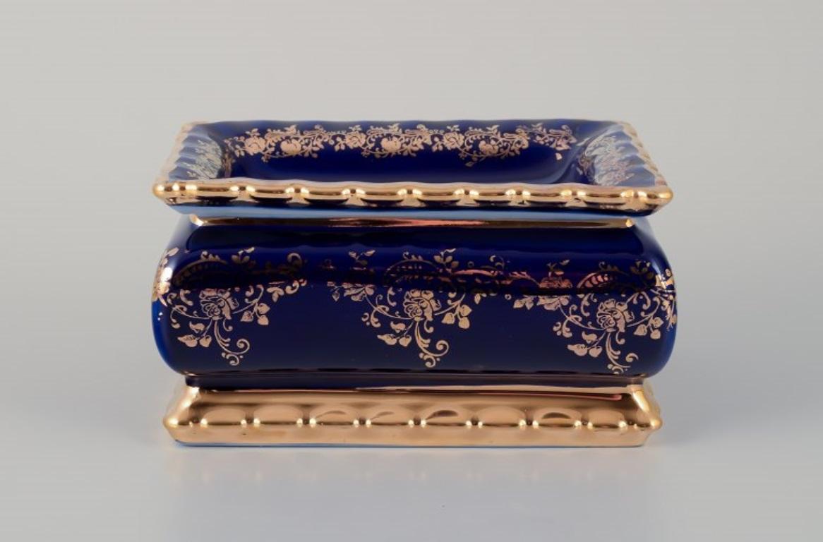 Limoges, France. A porcelain covered box decorated with 22-karat gold leaf and beautiful royal blue glaze. Scène galante. 
Approximately 1970.
Provenance: From a large French private collection of Limoges porcelain.
Marked.
In perfect