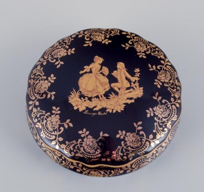 Limoges, Francia. Dos tarros/cajas tapados de porcelana, uno ovalado, decorado con pan de oro de 22 quilates y hermoso vidriado azul real. Escena galante. 
Aproximadamente 1970.
Procedencia: Procedente de una gran colección privada francesa de