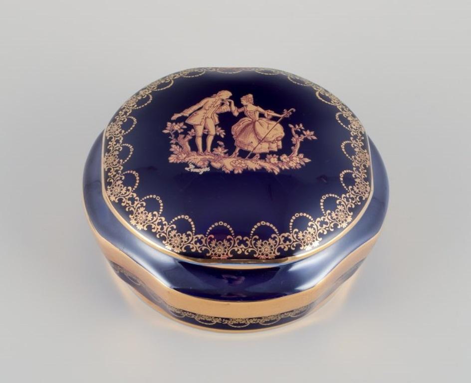 Limoges, Francia. Dos tarros de porcelana con tapa, decorados con pan de oro de 22 quilates y un hermoso vidriado azul real. Escena galante. 
Aproximadamente 1970.
Procedencia: Procedente de una gran colección privada francesa de porcelana de
